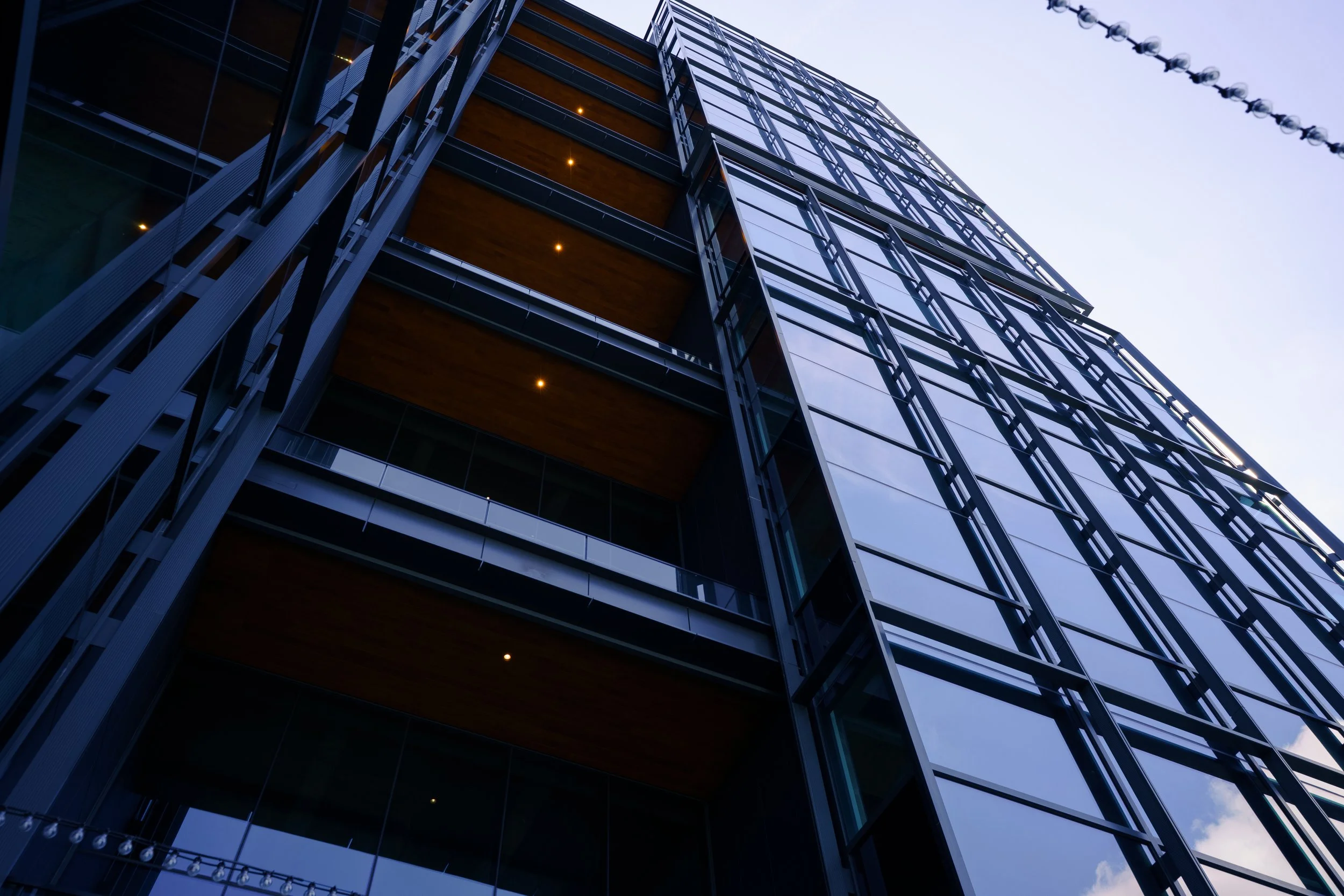Low-angle view of a modern glass and steel high-rise building against a light sky.