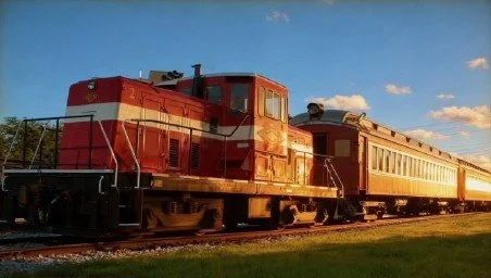 A red and cream train on railway tracks during sunset.