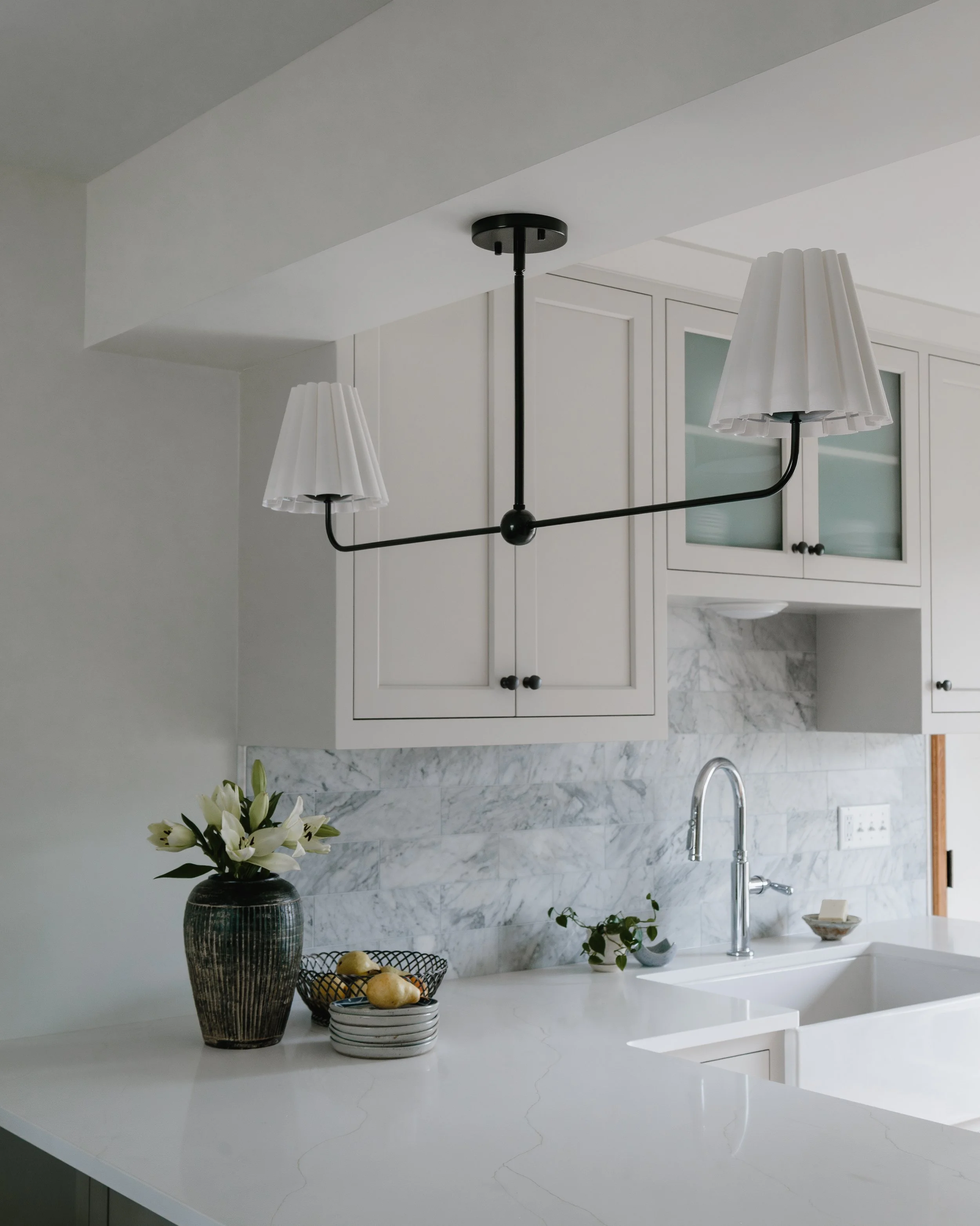 Kitchen renovation featuring white cabinets, marble backsplash, and modern lighting in Twin Cities historic home