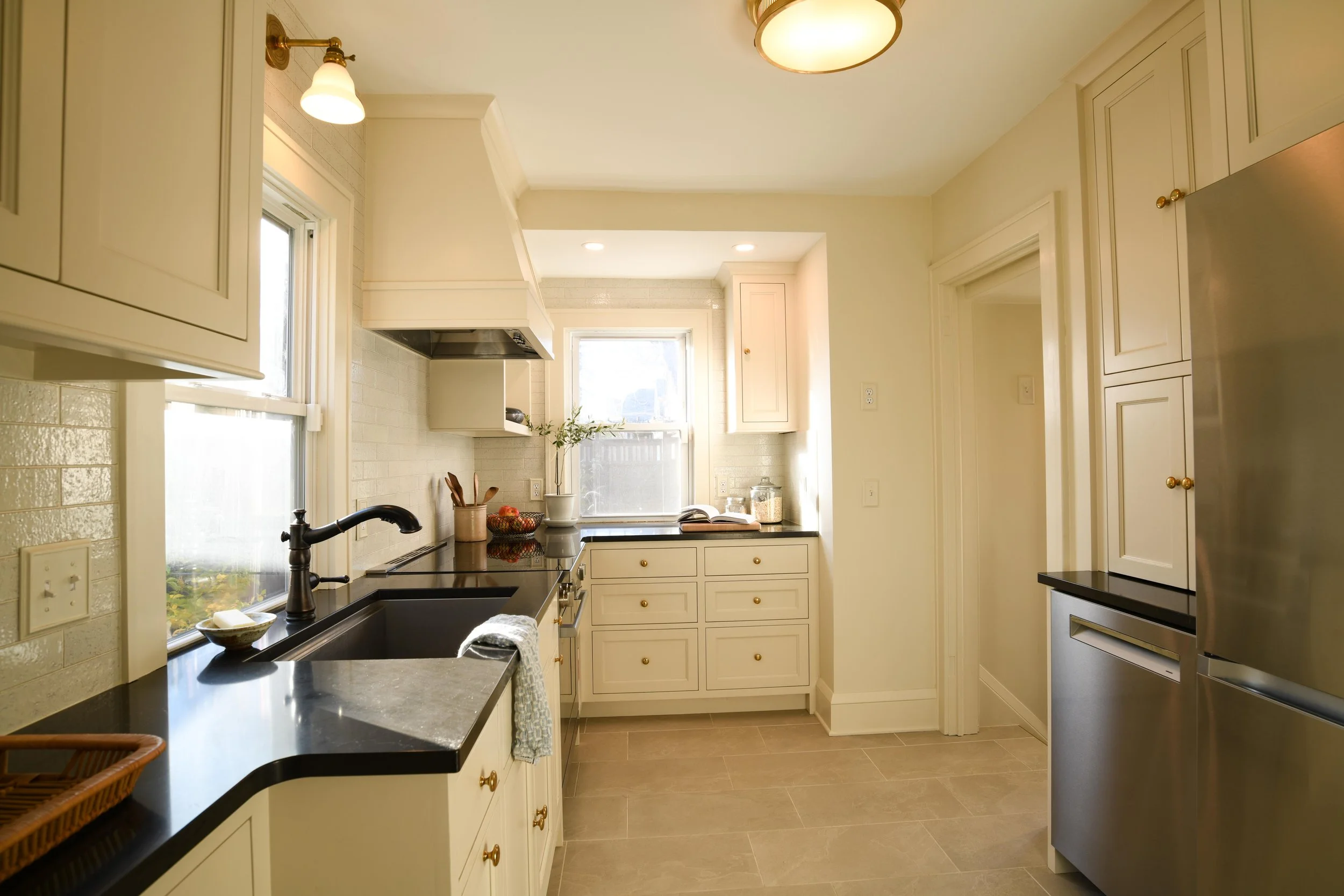 Galley kitchen renovation with white cabinets, dark countertops, and stainless appliances in Minneapolis historic home