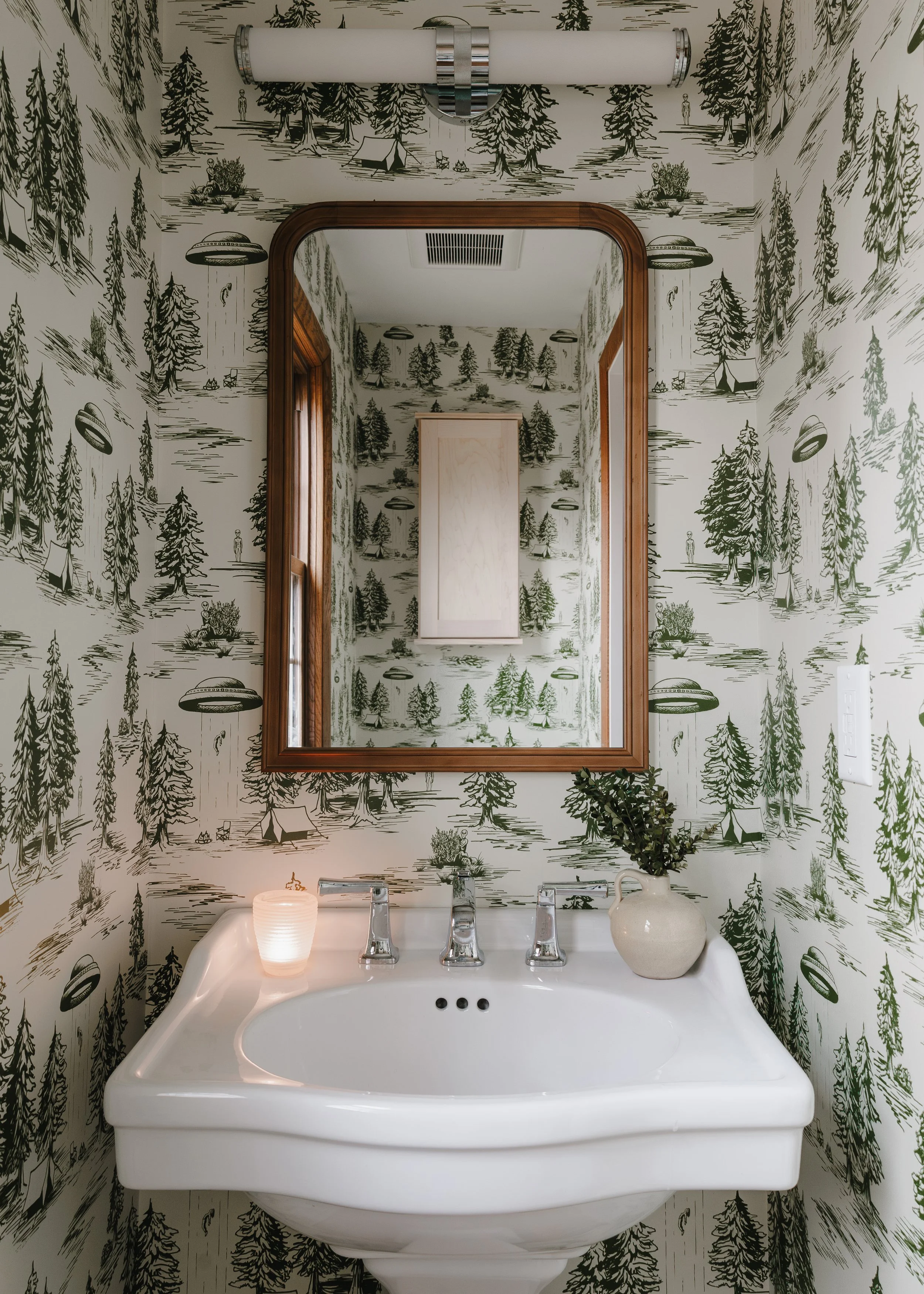 Powder room renovation with woodland wallpaper, wood-framed mirror, and pedestal sink in Minneapolis historic home