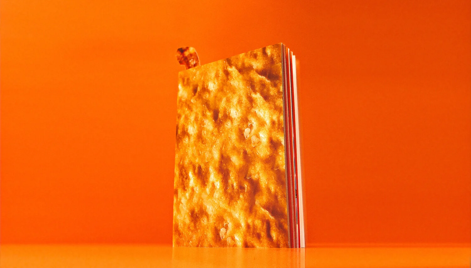 A vertically standing phone with a fiery orange and yellow abstract design on the screen, against an orange background.