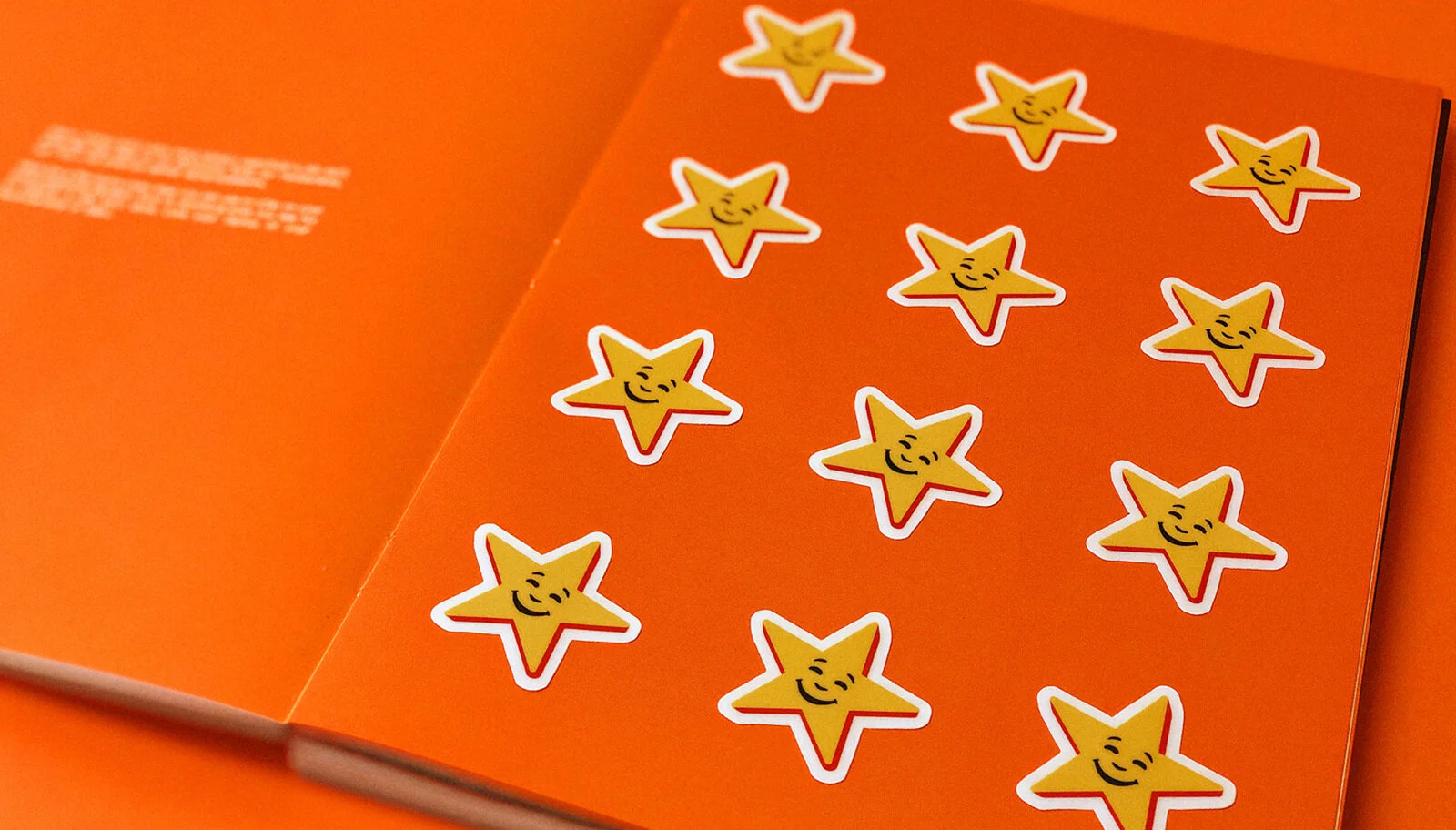 Orange box with multiple yellow star stickers featuring smiling faces scattered on the surface.