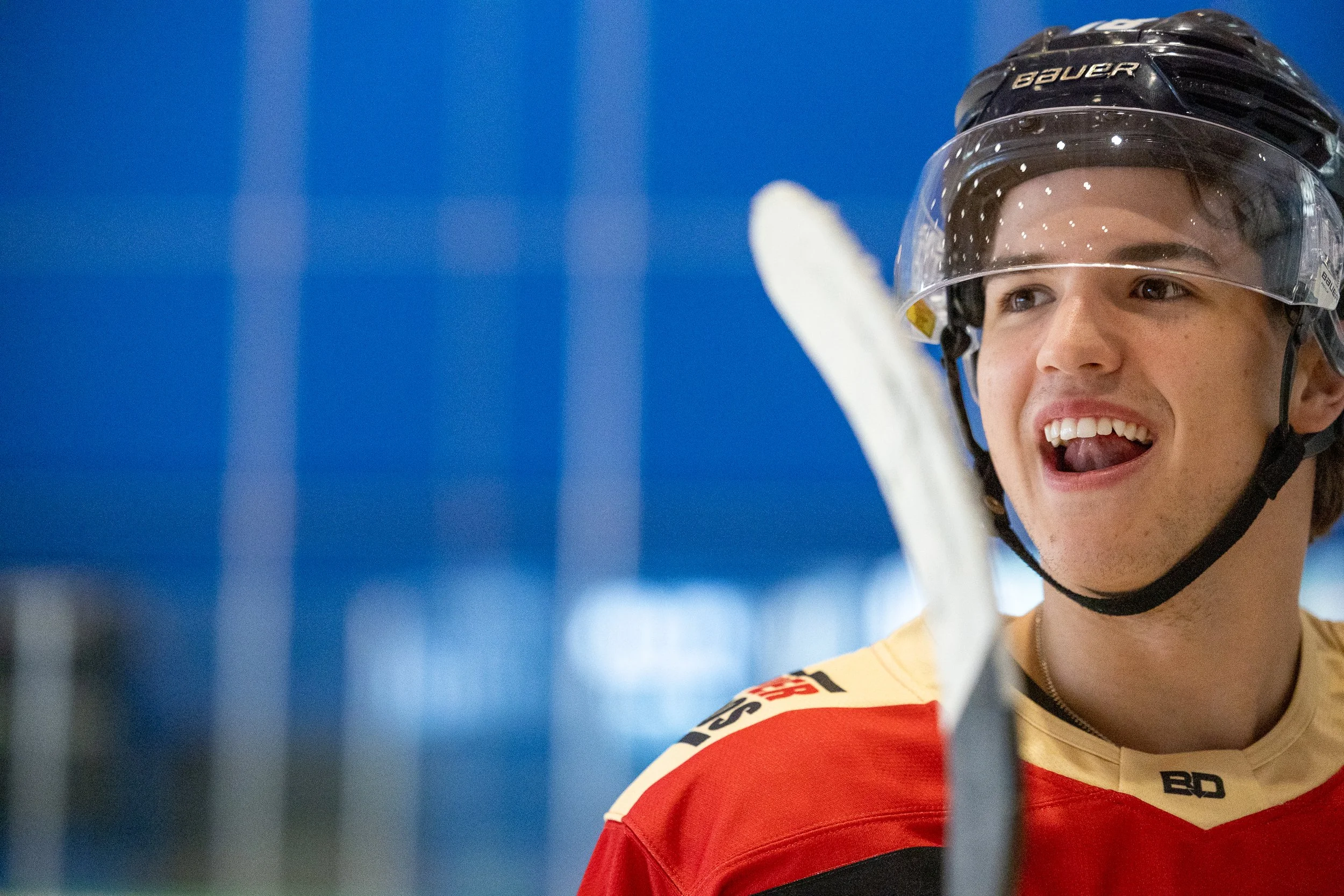 A close up on a young hockey player wearing a helmet and smiling