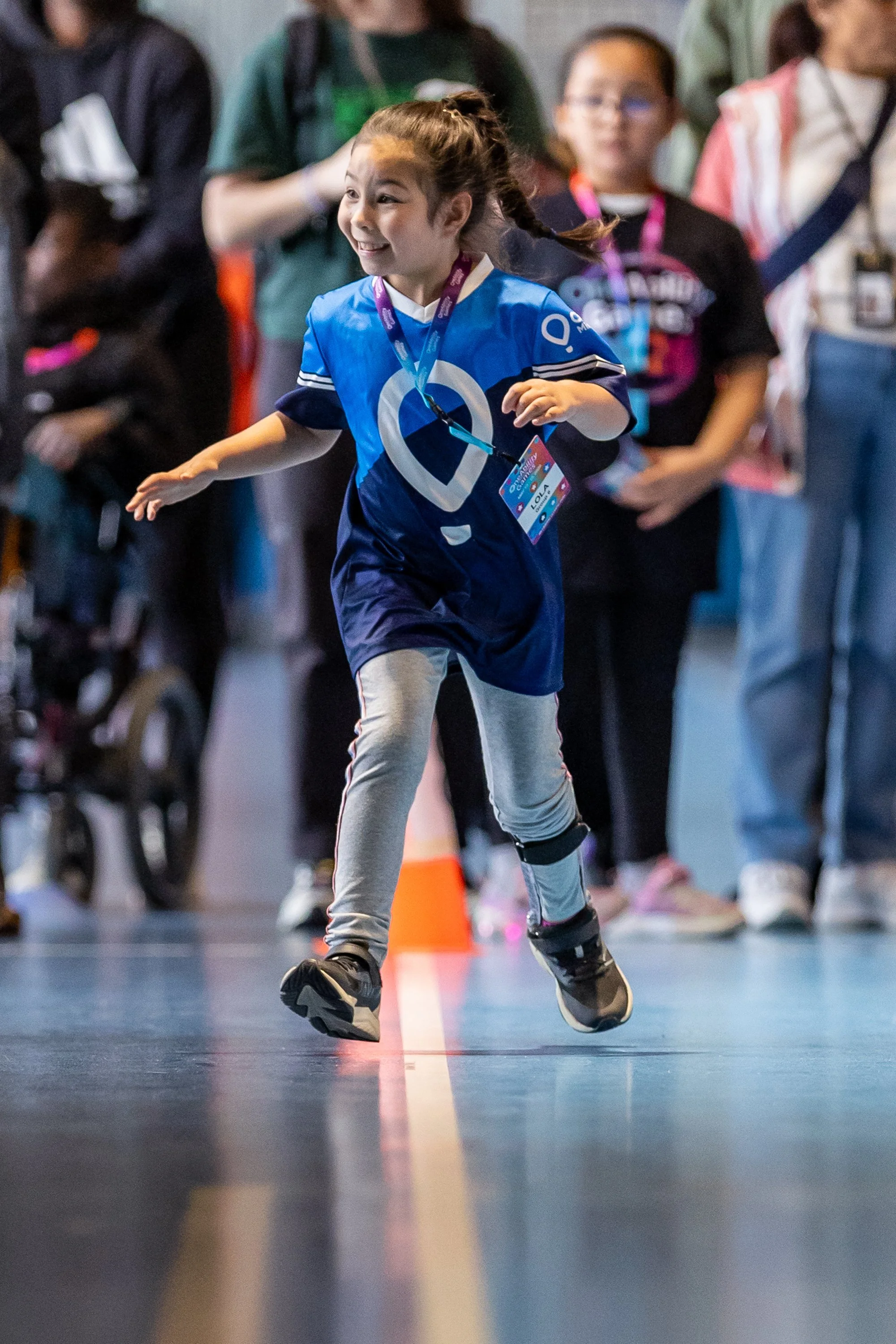 A young girl races down a track with a big smile on her face