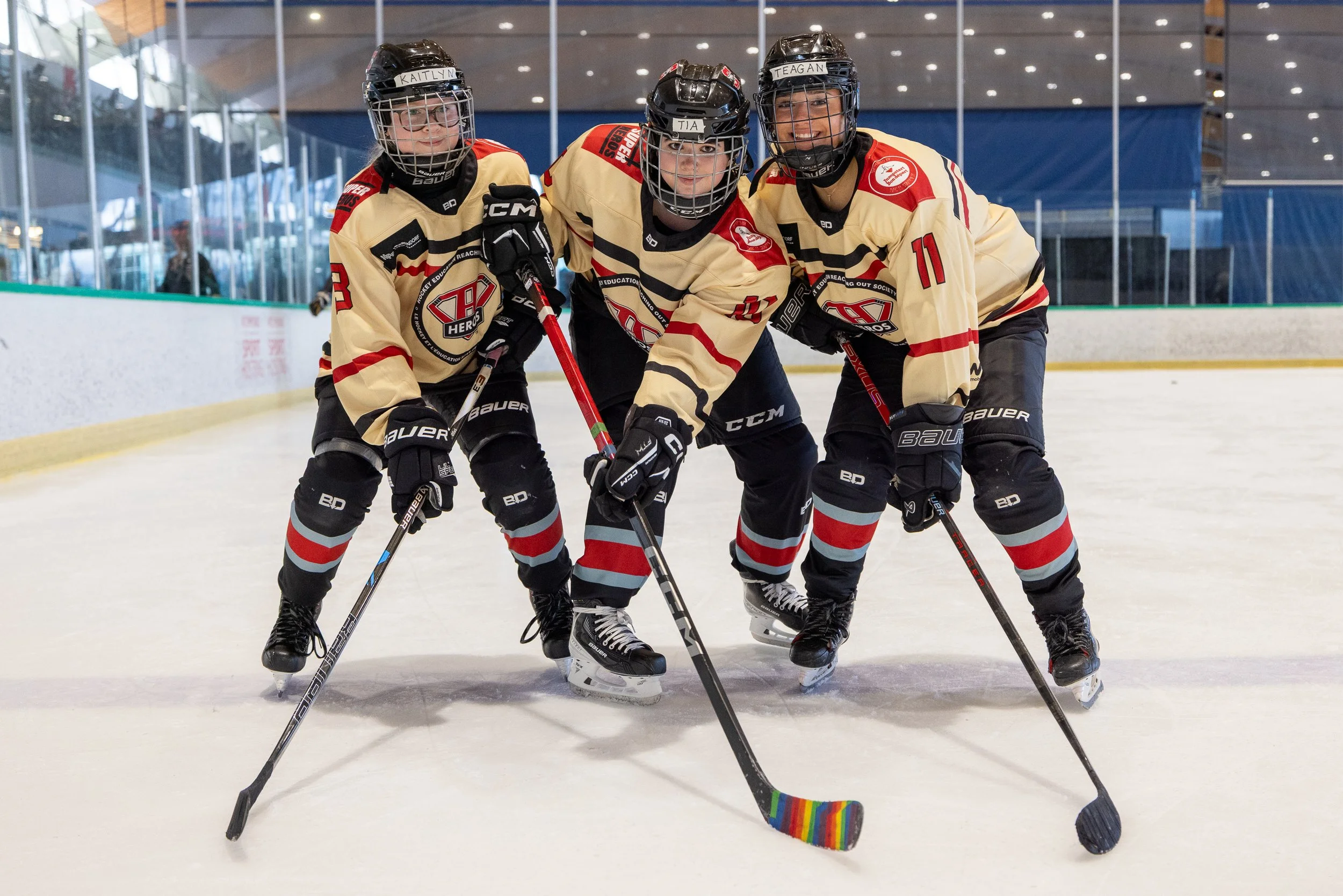 Three young SuperHeros Hockey players stand on the ice together in full hockey gear