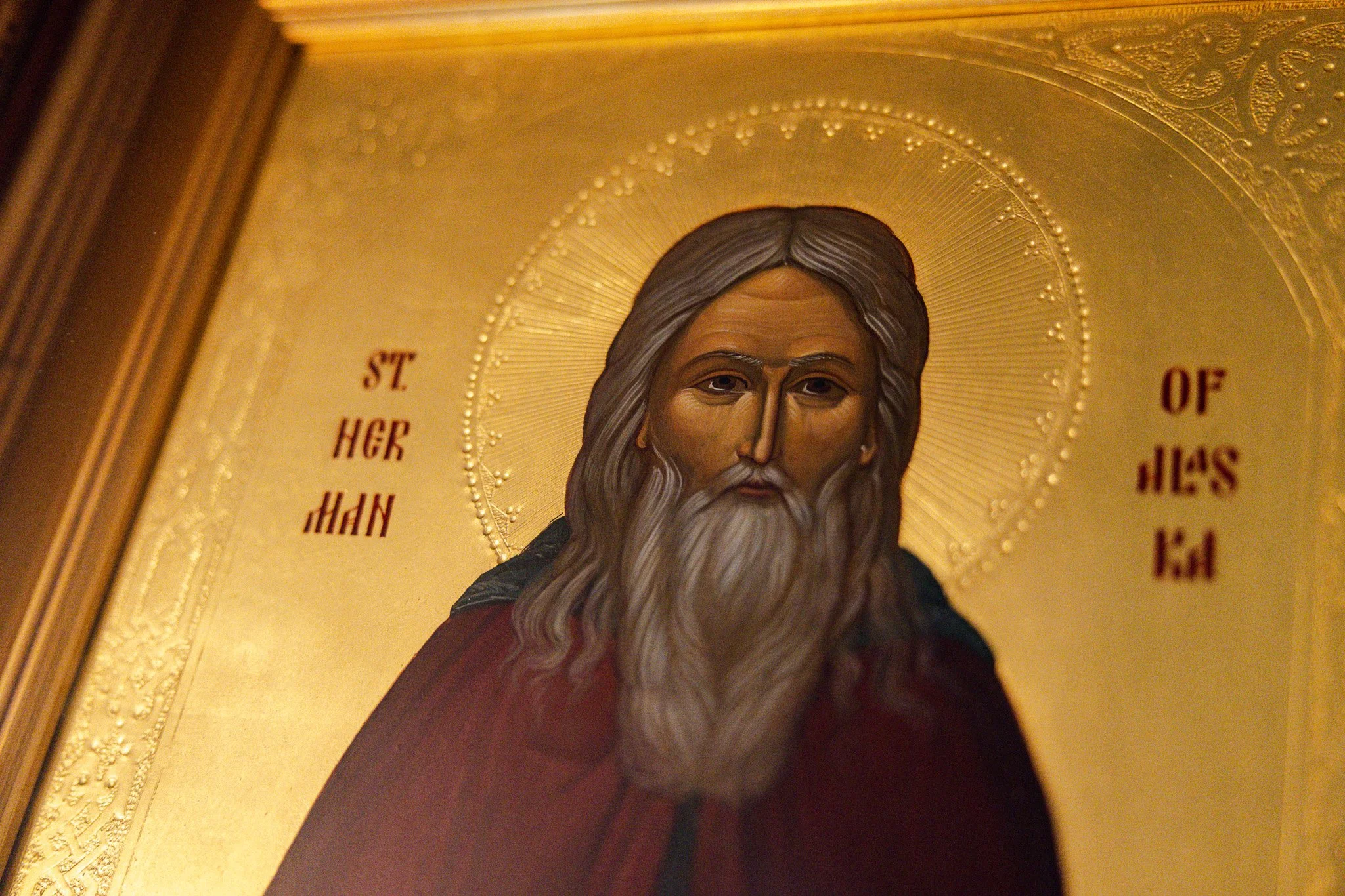 Religious icon of St. Herman of Alaska with a golden background, featuring a halo, long hair, and a beard,