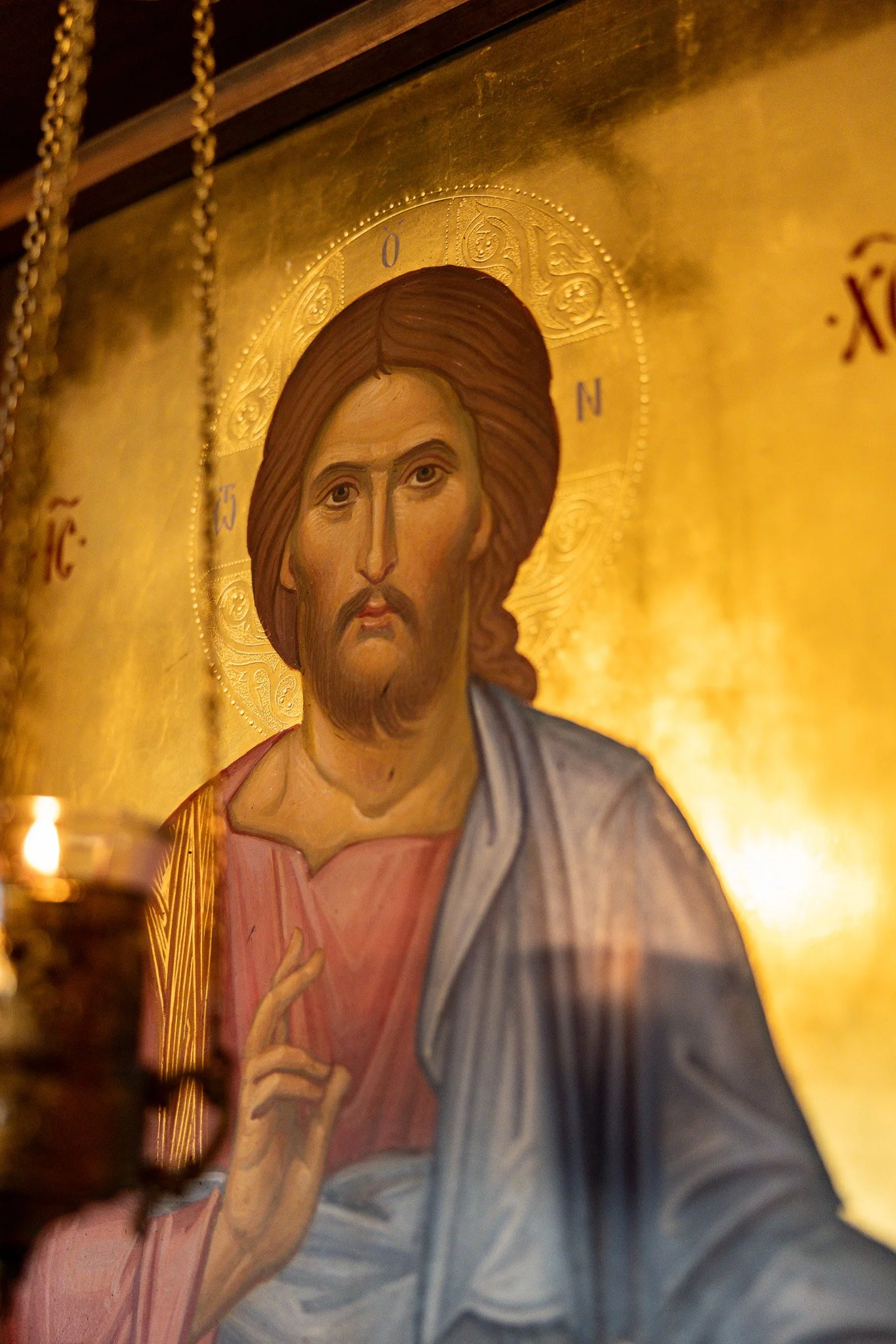 Religious icon depicting Jesus Christ with a golden background, long brown hair, and a beard, making a blessing gesture with his right hand.