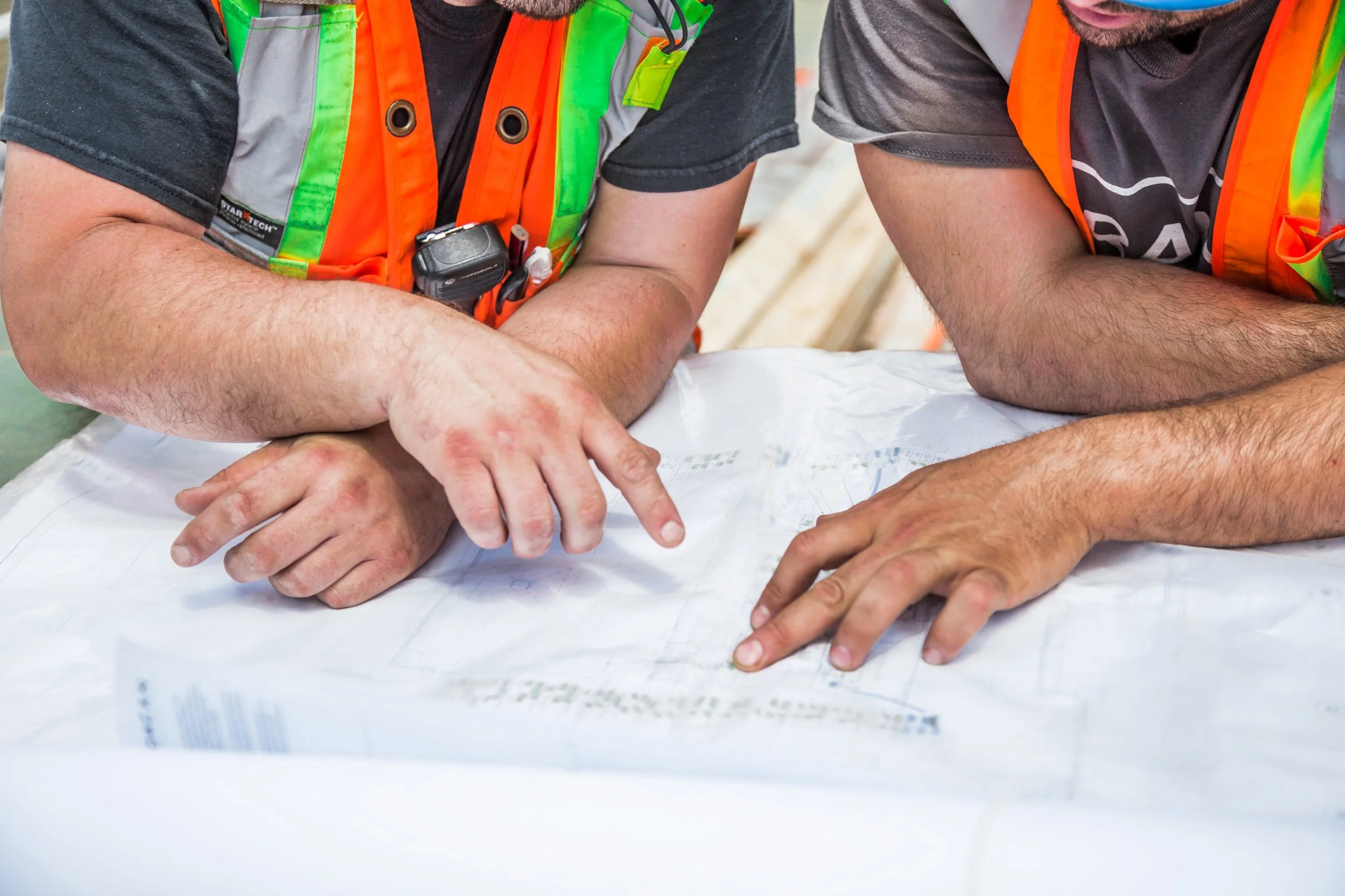 Construction workers examining blueprints on a table.