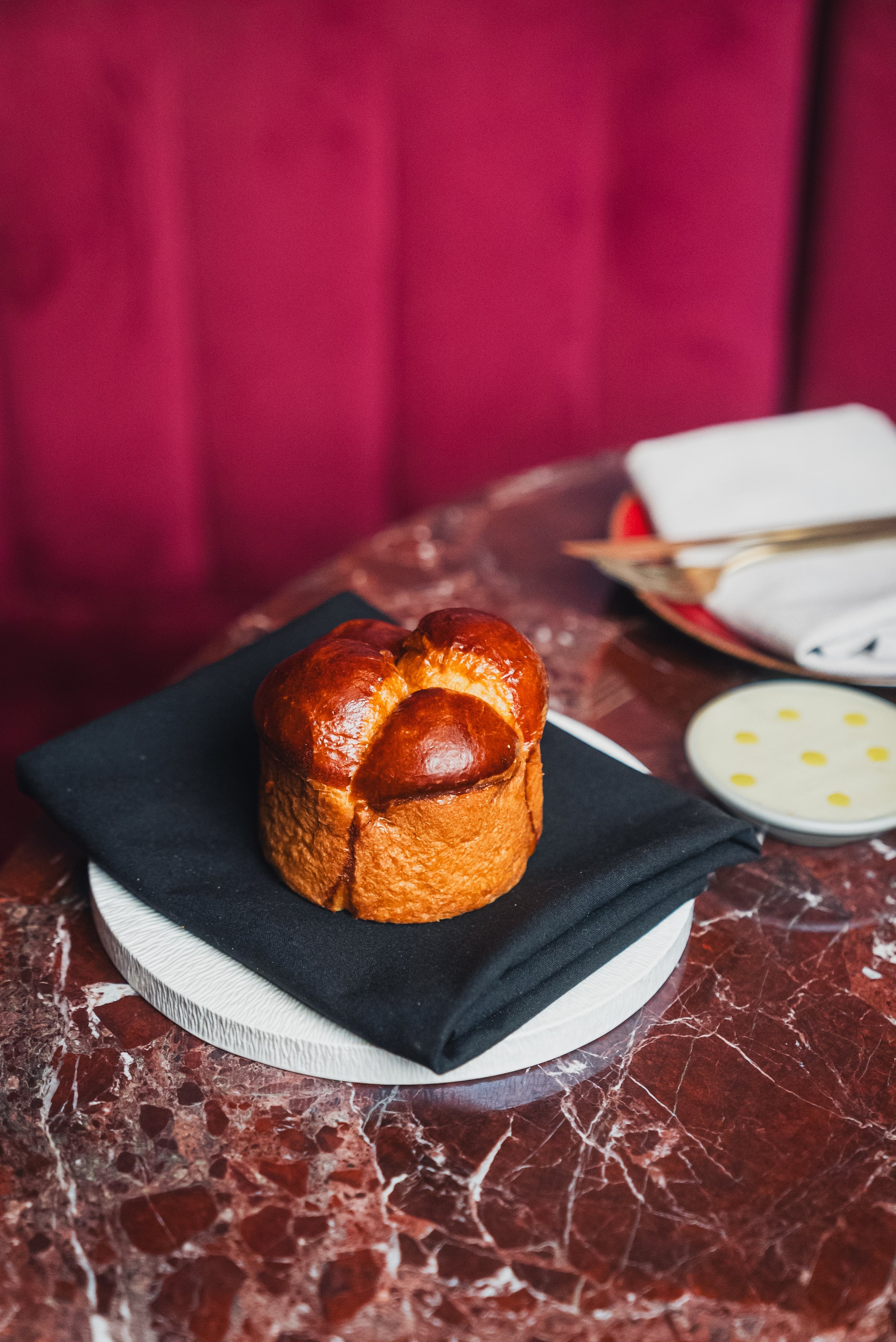 Brioche bread on a black napkin on a marble table with a blurred background.