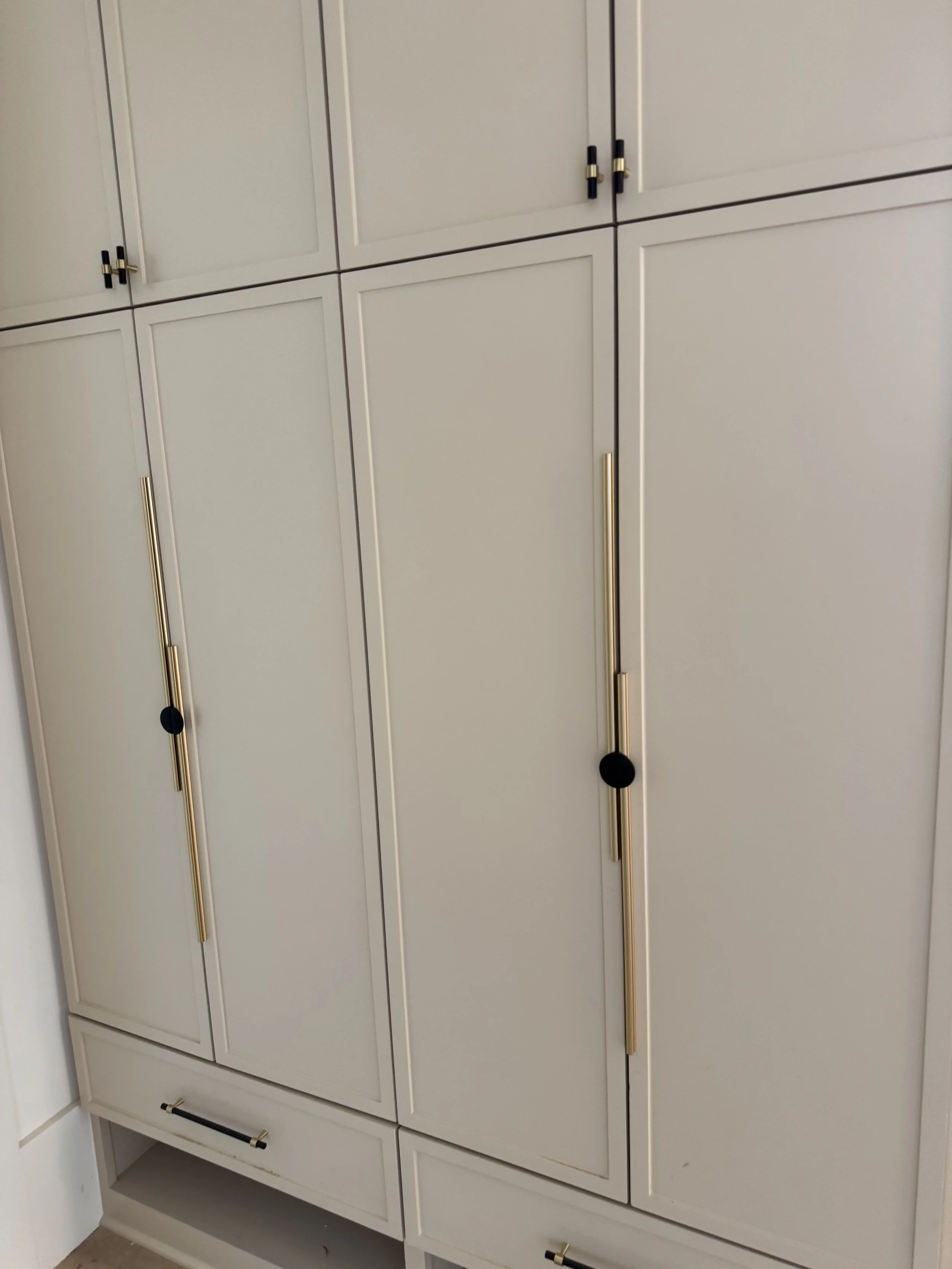 Modern interior with large window showing a tree and street outside, black and wood-colored built-in furniture, and open shelves in a room.