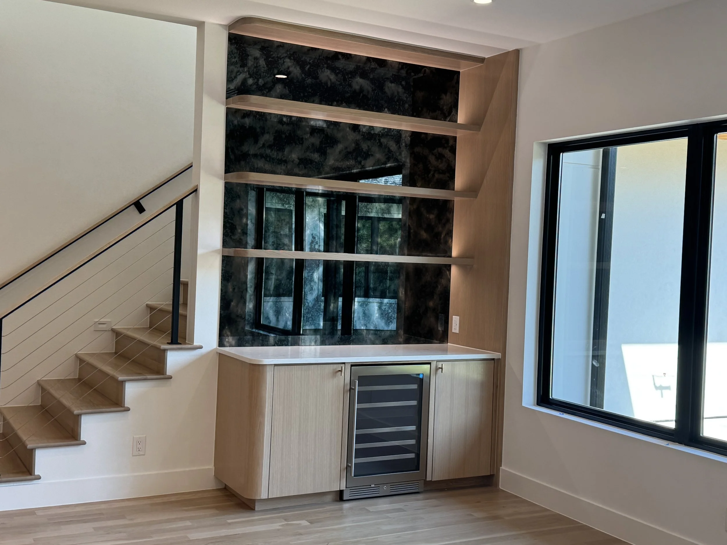 Modern bathroom featuring a freestanding bathtub, a large mirror, wooden cabinetry, pink orchids on a marble countertop, and a shower area with multiple water fixtures.