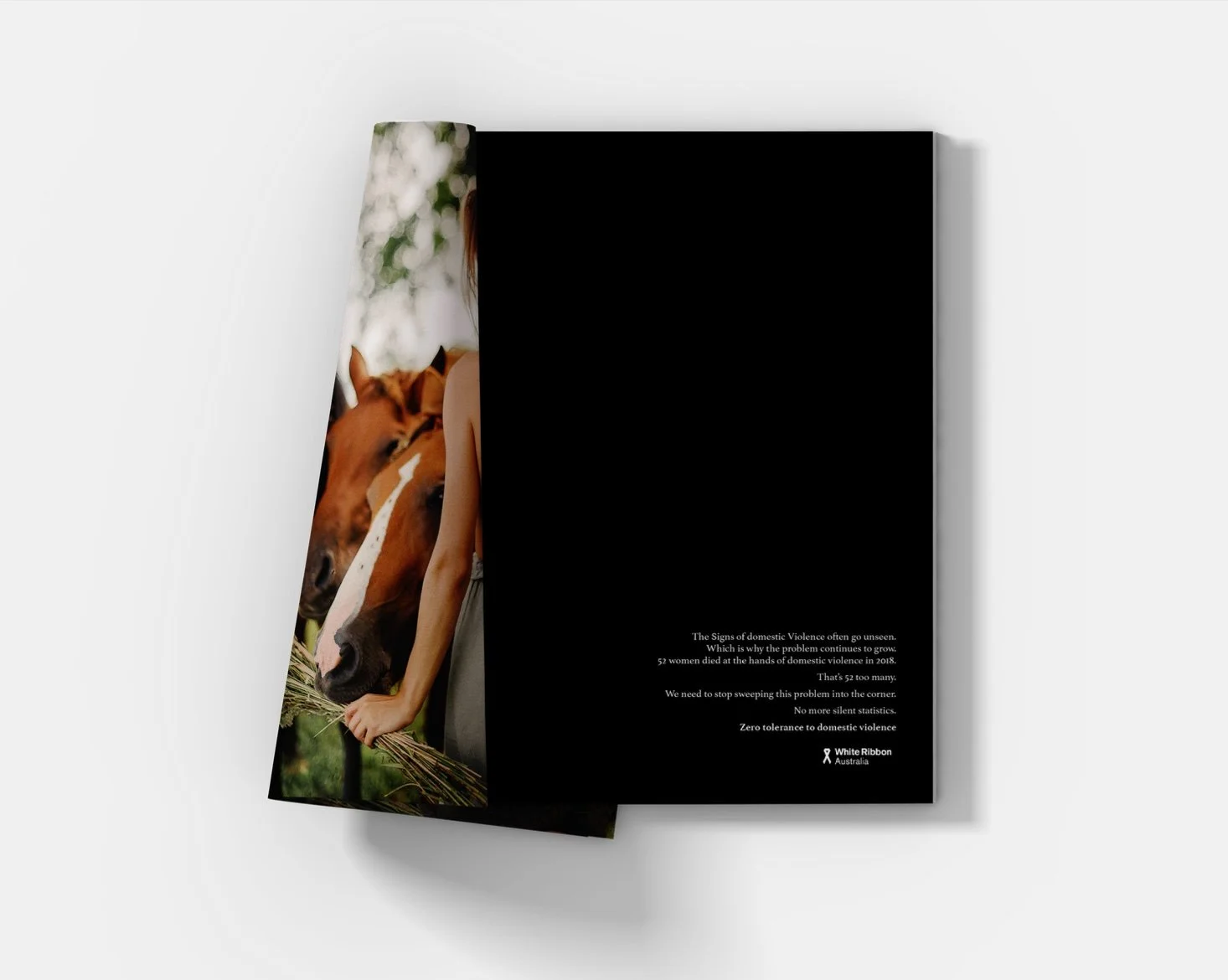 Open booklet with a partial image of a woman with a horse on the left page and black background with white text on the right page, promoting awareness about domestic violence in Australia.