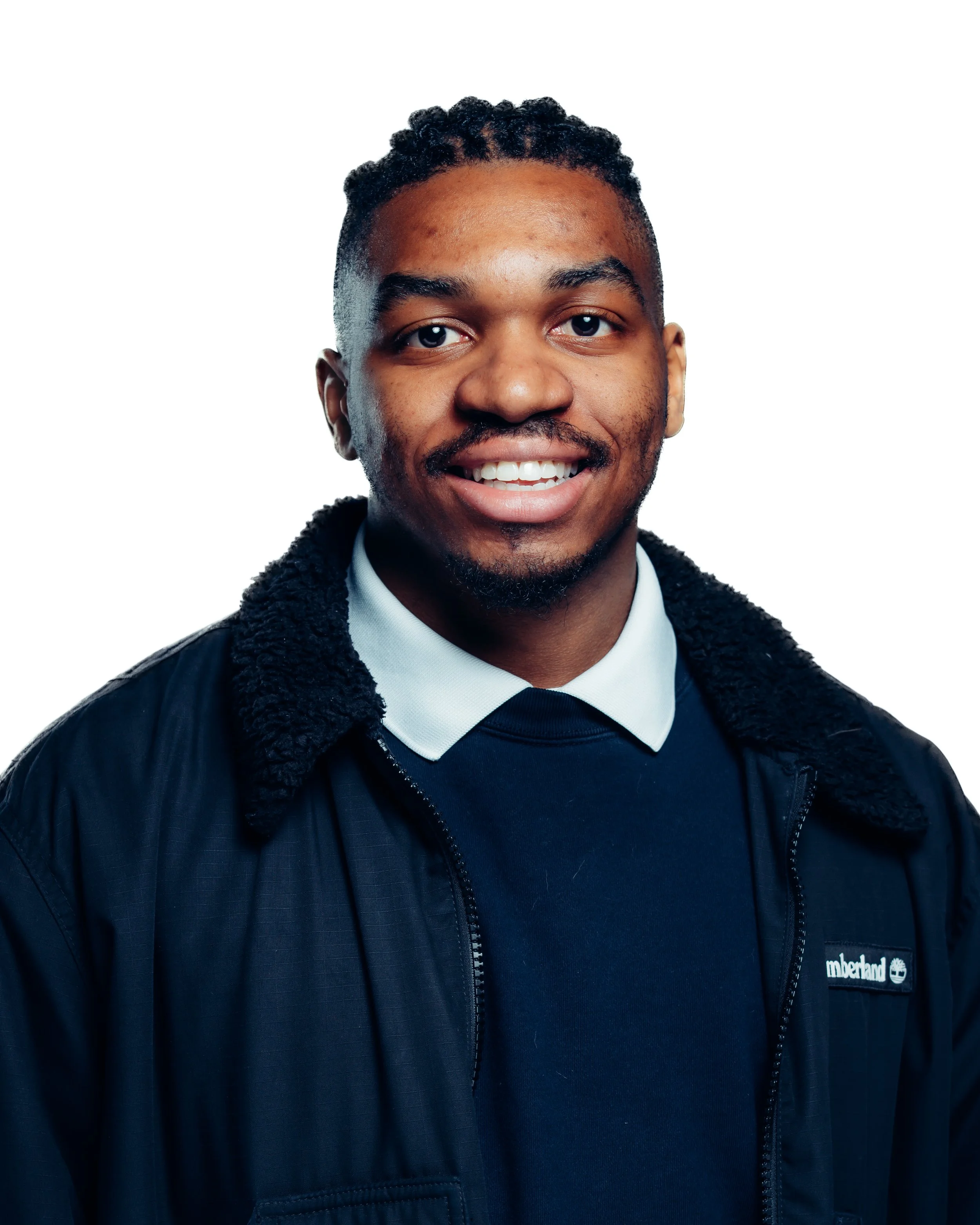 Man with dark hair and a dark jacket in front of a white background
