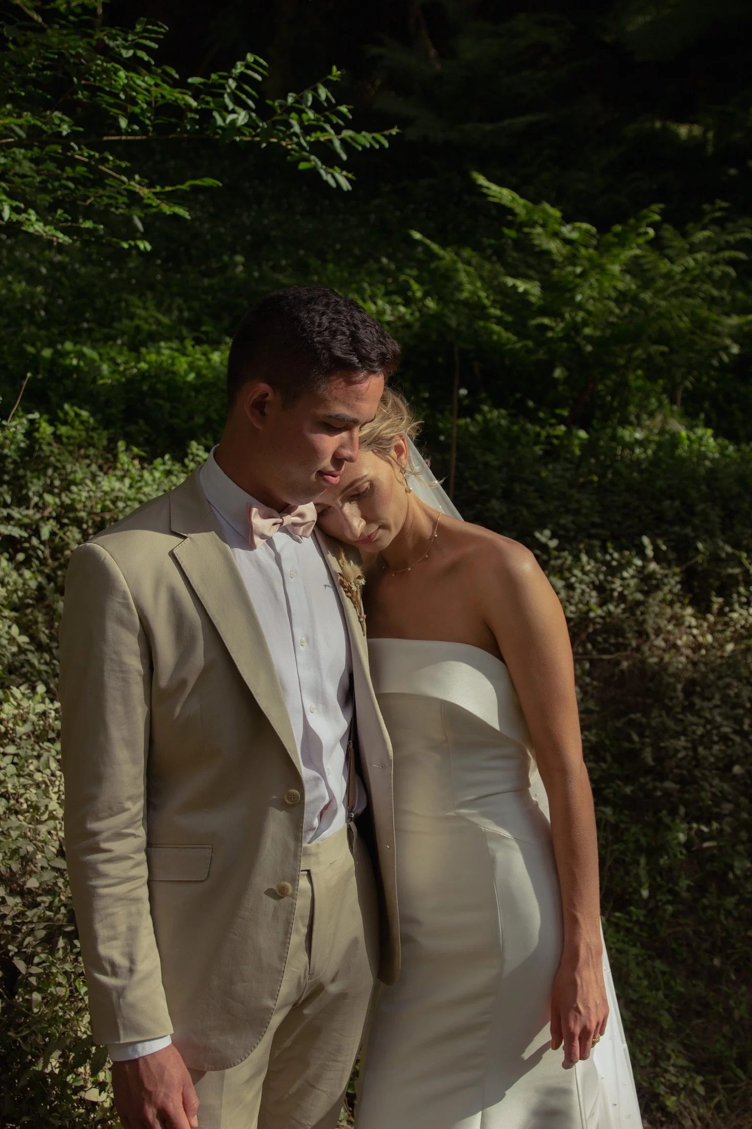 A bride and groom with their eyes closed, leaning their heads together in a peaceful moment outdoors surrounded by greenery.  Wedding Photography Waikato New Zealand. Wedding Photography Hamilton New Zealand. Northland Wedding Photography