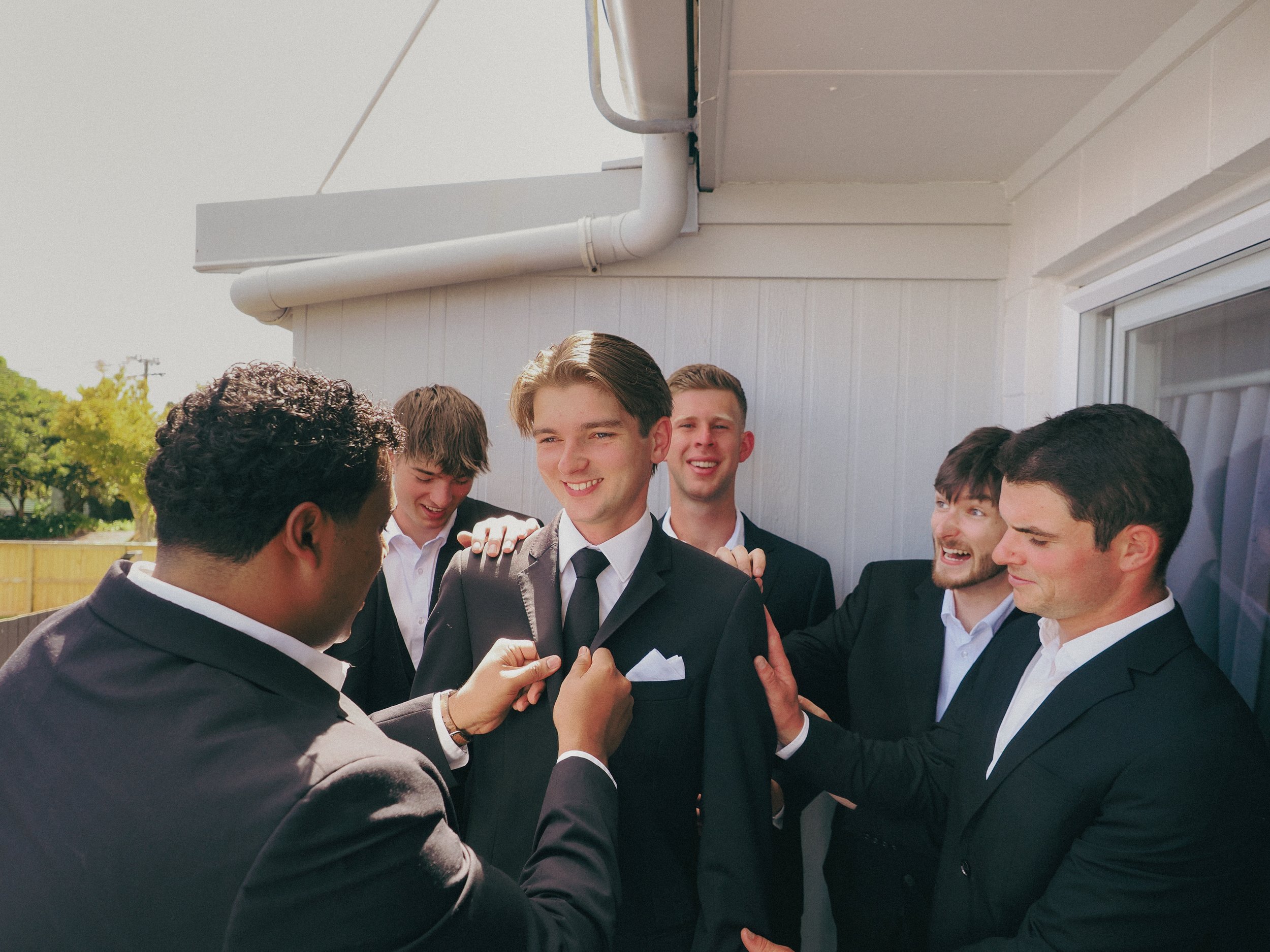 Young men in suits participating in a wedding ceremony, with one man putting a ring on another man's finger.