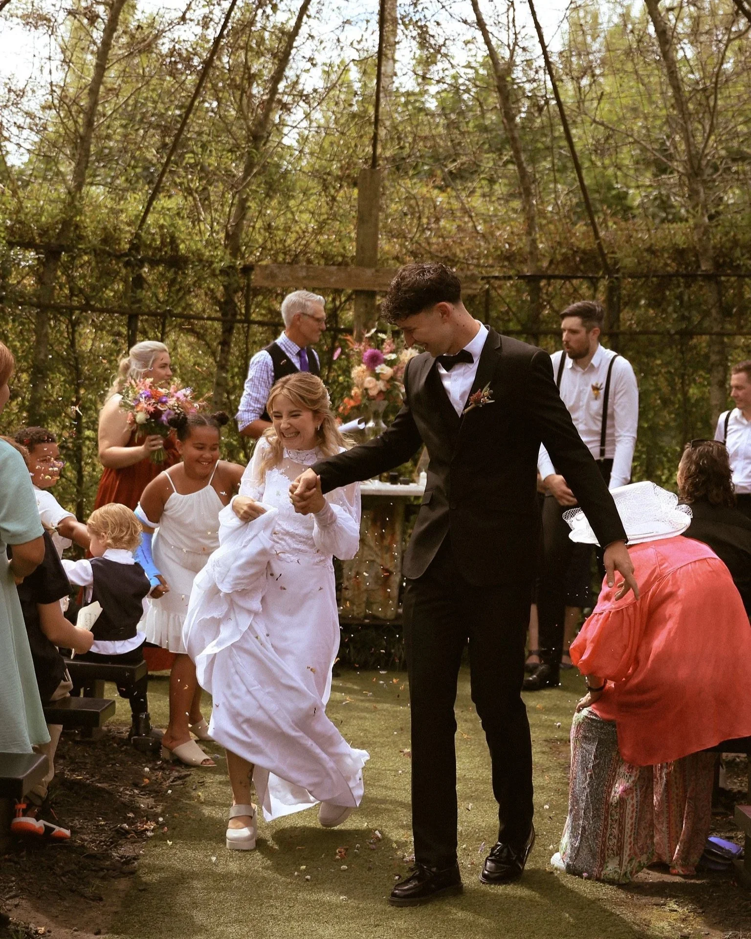 People celebrating a wedding outdoors, with the bride and groom dancing while others watch and enjoy the moment.