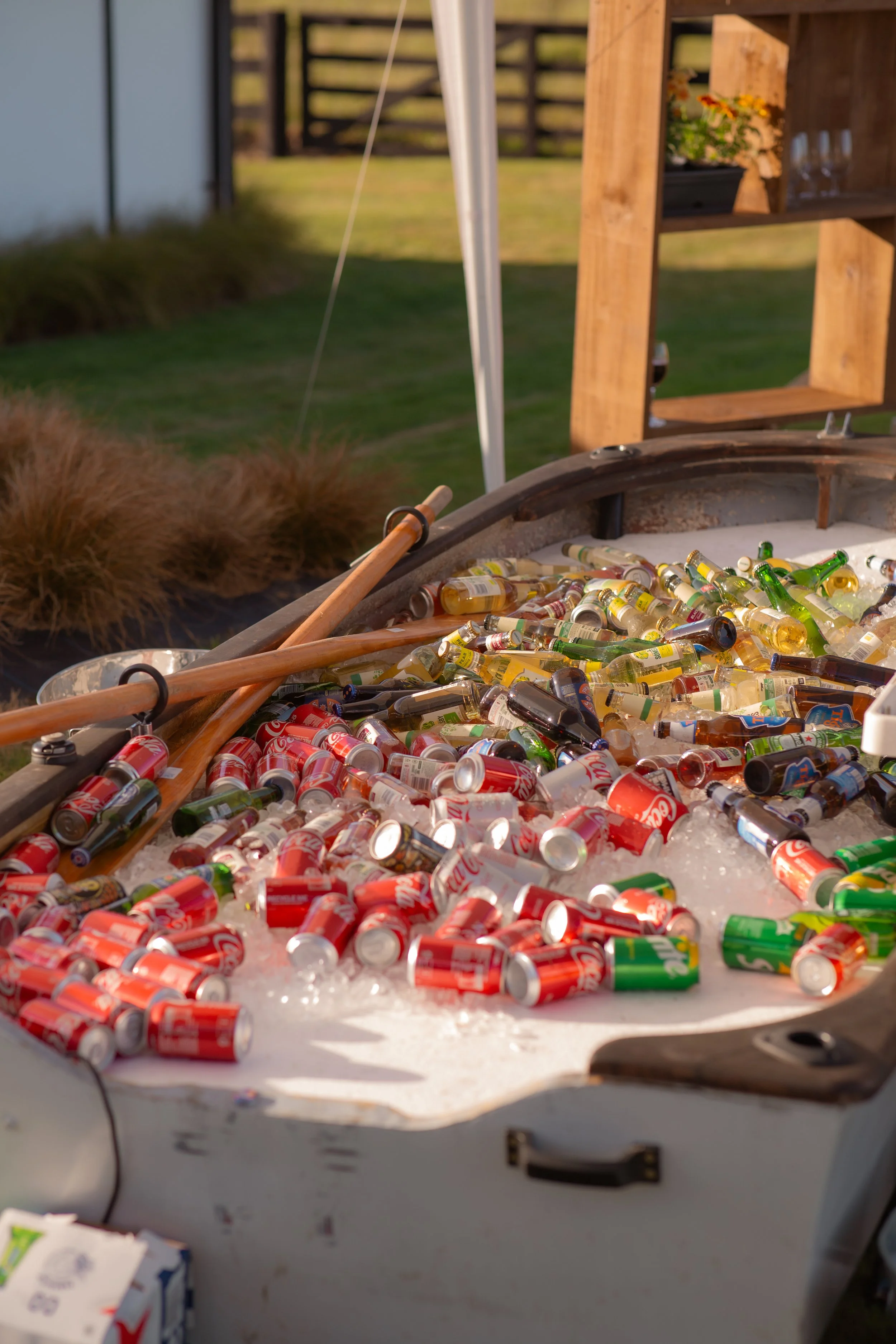 A cooler filled with ice and various cans of soda, including Red Coca-Cola and Sprite bottles, with two wooden paddles resting on top.  Wedding Photography Waikato New Zealand. Wedding Photography Hamilton New Zealand. Northland Wedding Photography