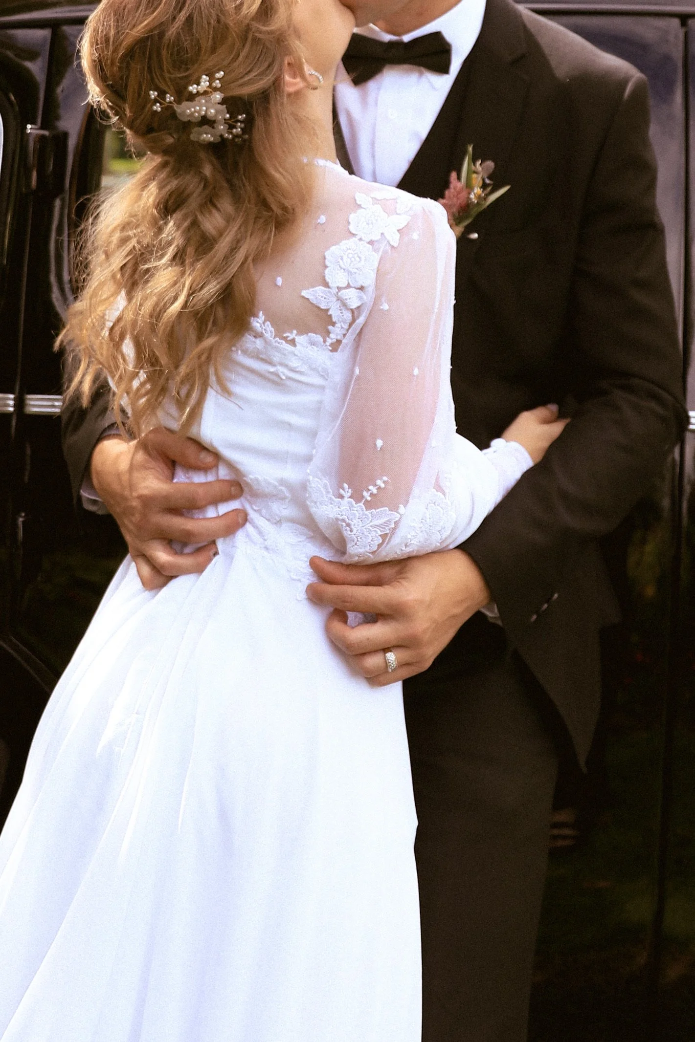 A bride and groom share a kiss during their wedding, with the bride wearing a white lace wedding dress and the groom in a black tuxedo, holding each other close. Wedding Photography Waikato New Zealand. Wedding Photography Hamilton New Zealand