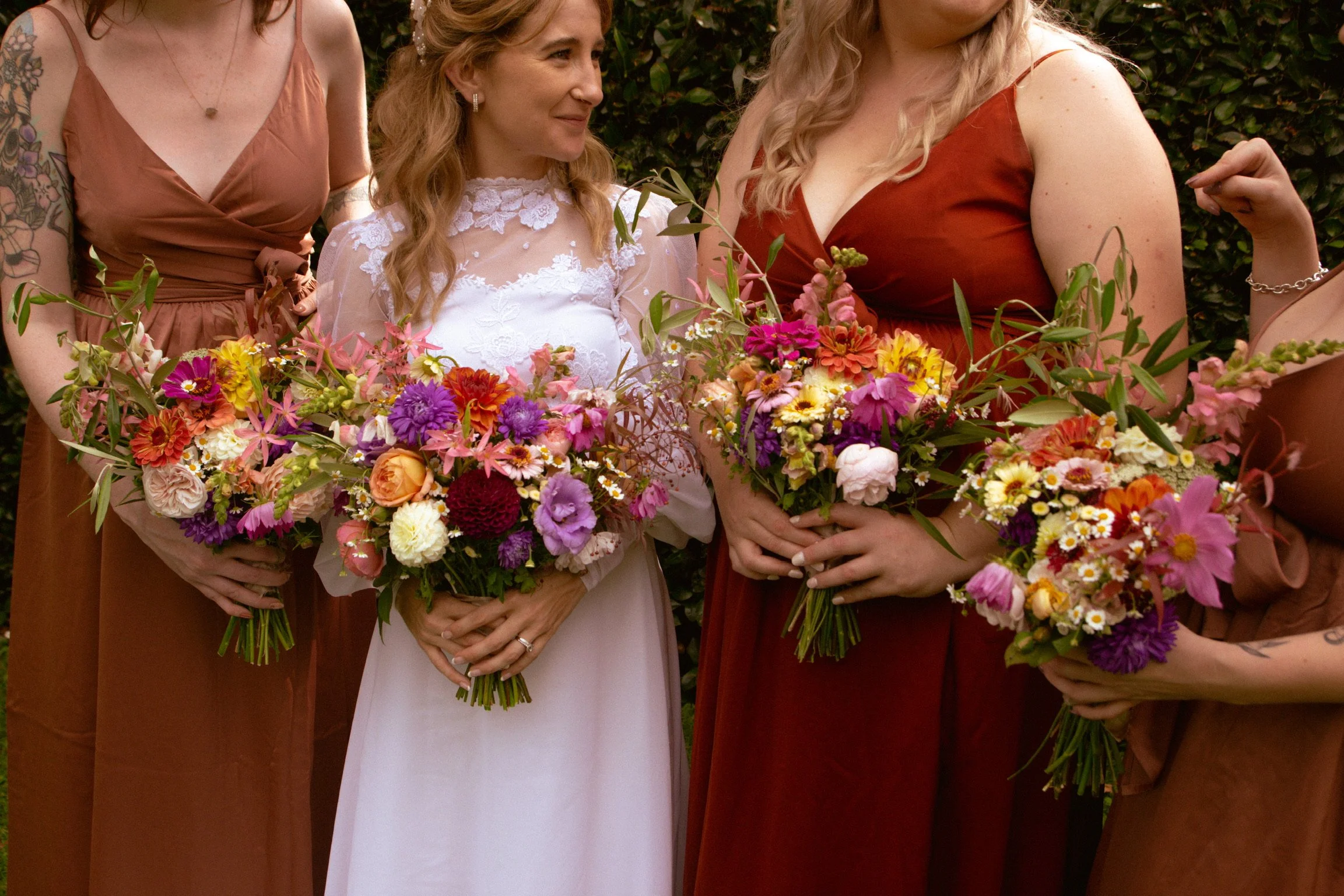 Women in dresses holding colorful flower bouquets at a celebration or wedding. Wedding Photography Waikato New Zealand. Wedding Photography Hamilton New Zealand