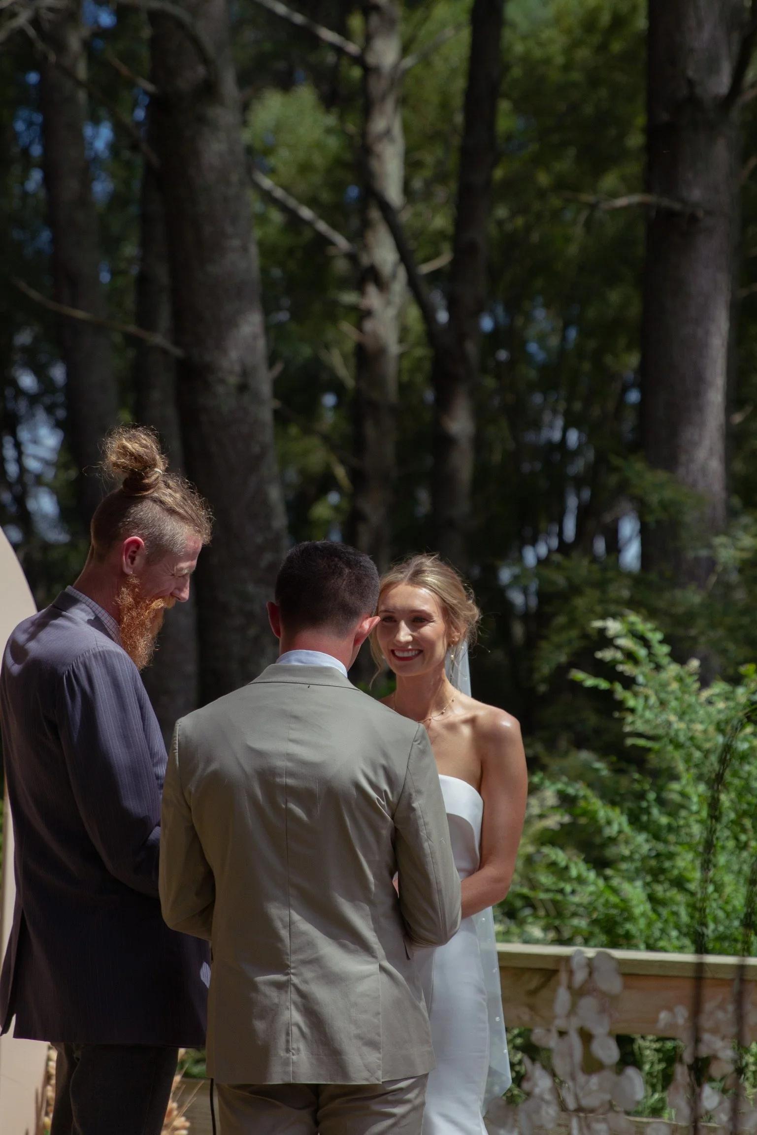 A bride and groom exchanging vows during a wedding ceremony outdoors in a wooded area.  Wedding Photography Waikato New Zealand. Wedding Photography Hamilton New Zealand. Northland Wedding Photography