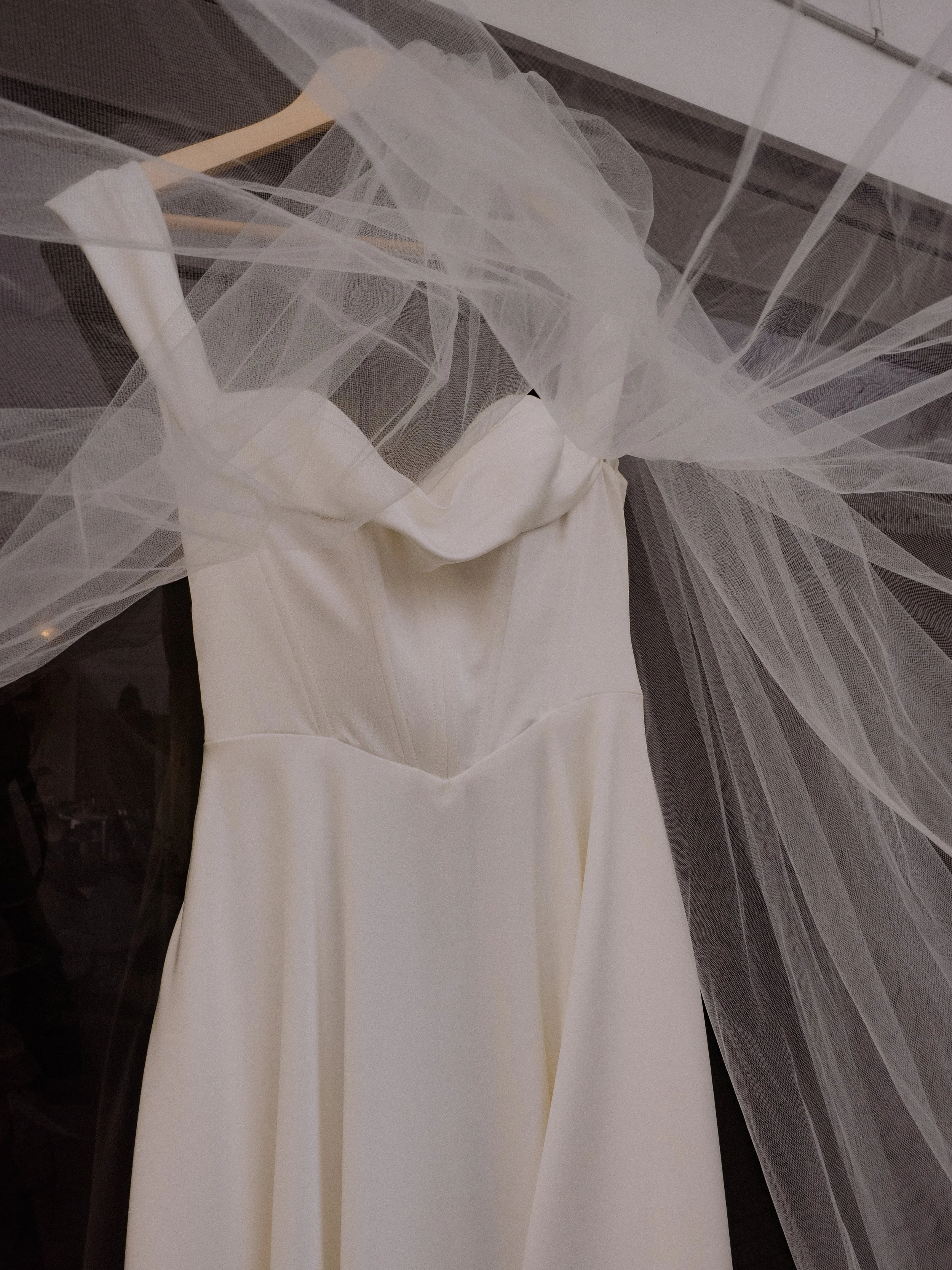 A white wedding dress hanging with a veil draped over it. Wedding Photography Waikato New Zealand. Wedding Photography Hamilton New Zealand. Northland Wedding Photography