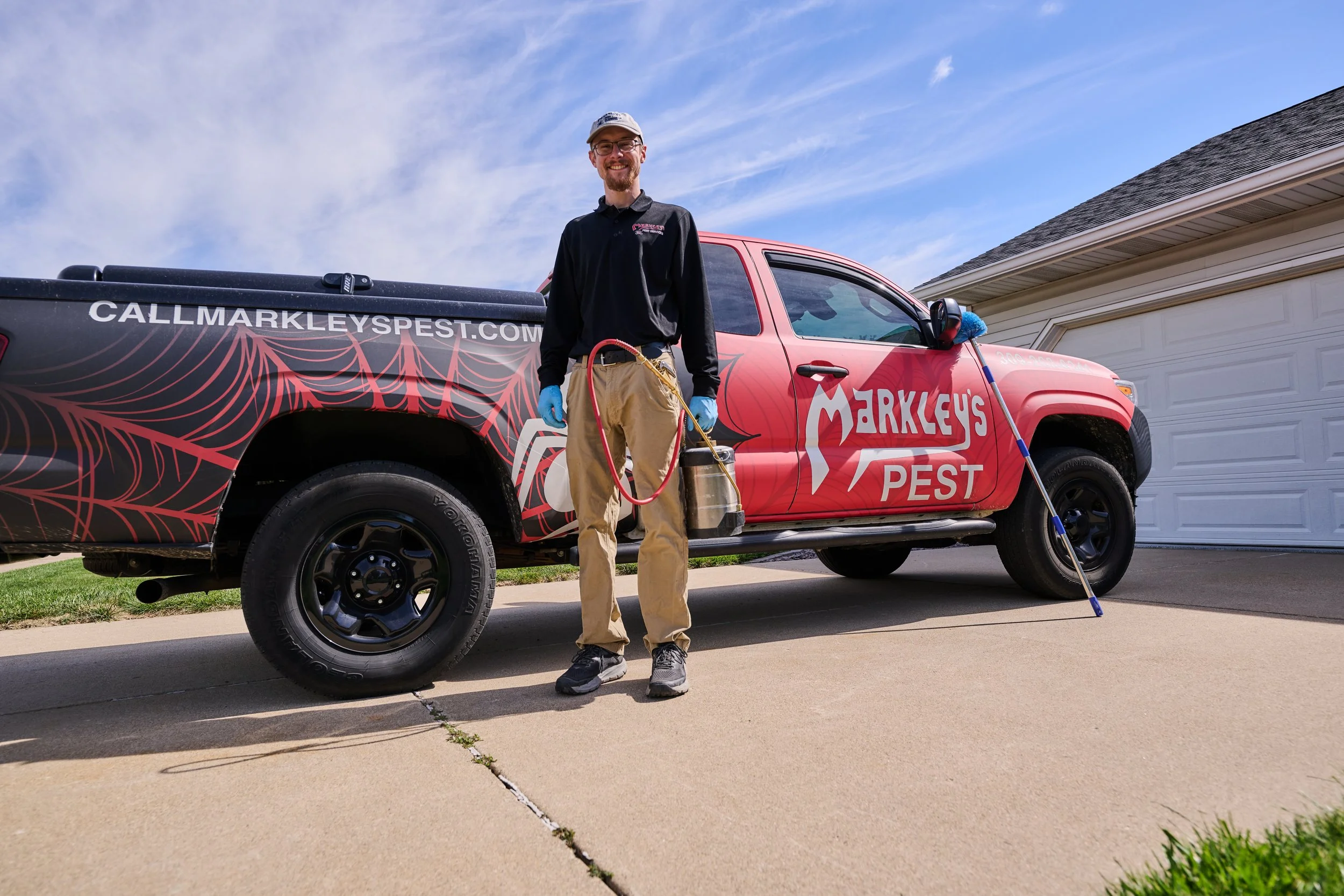 A Markley's Pest Elimination Services technician with equipment beside a branded service truck in Morton, Illinois.
