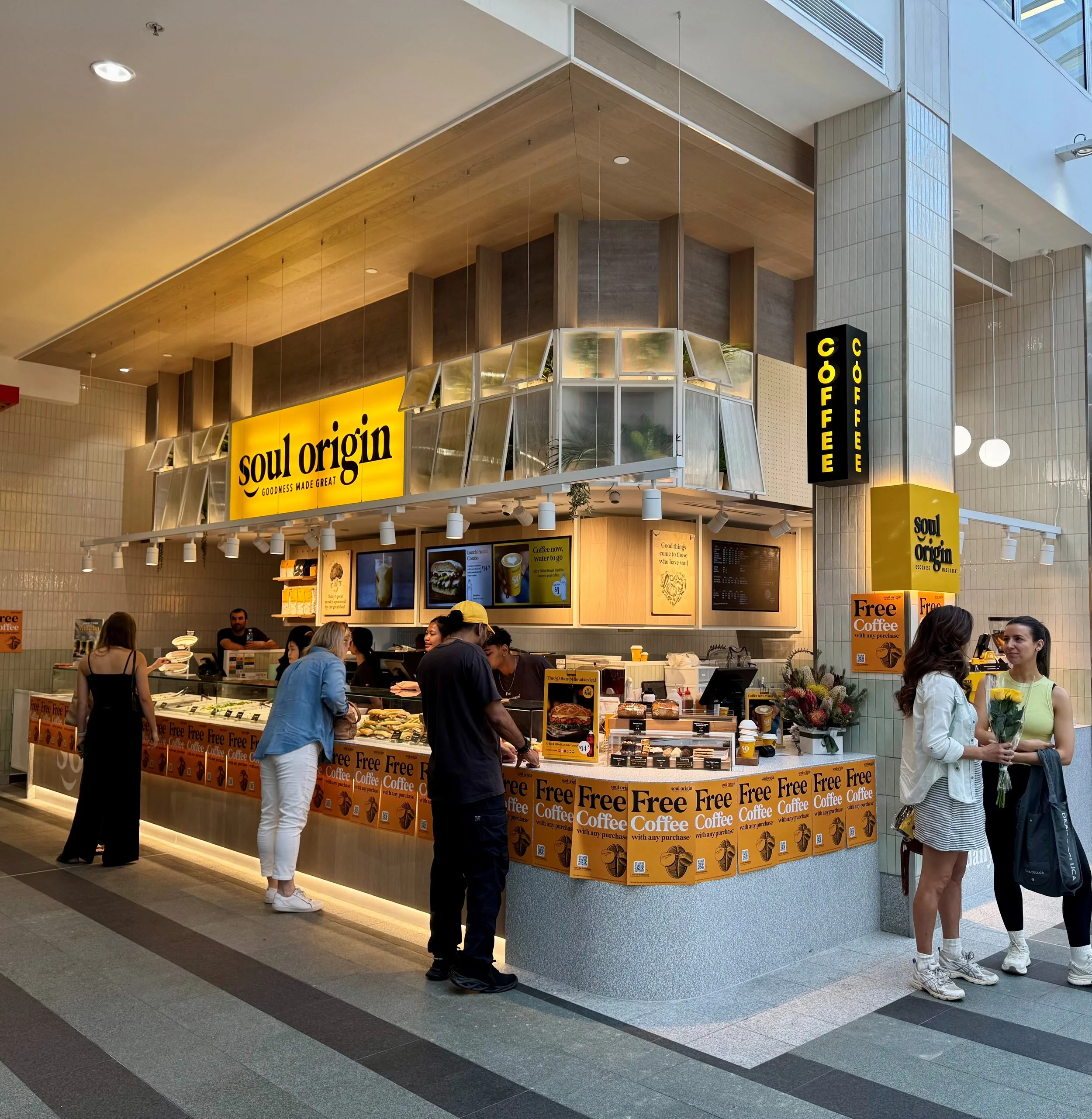 A coffee shop named Soul Origin inside a shopping mall with people ordering and socializing.