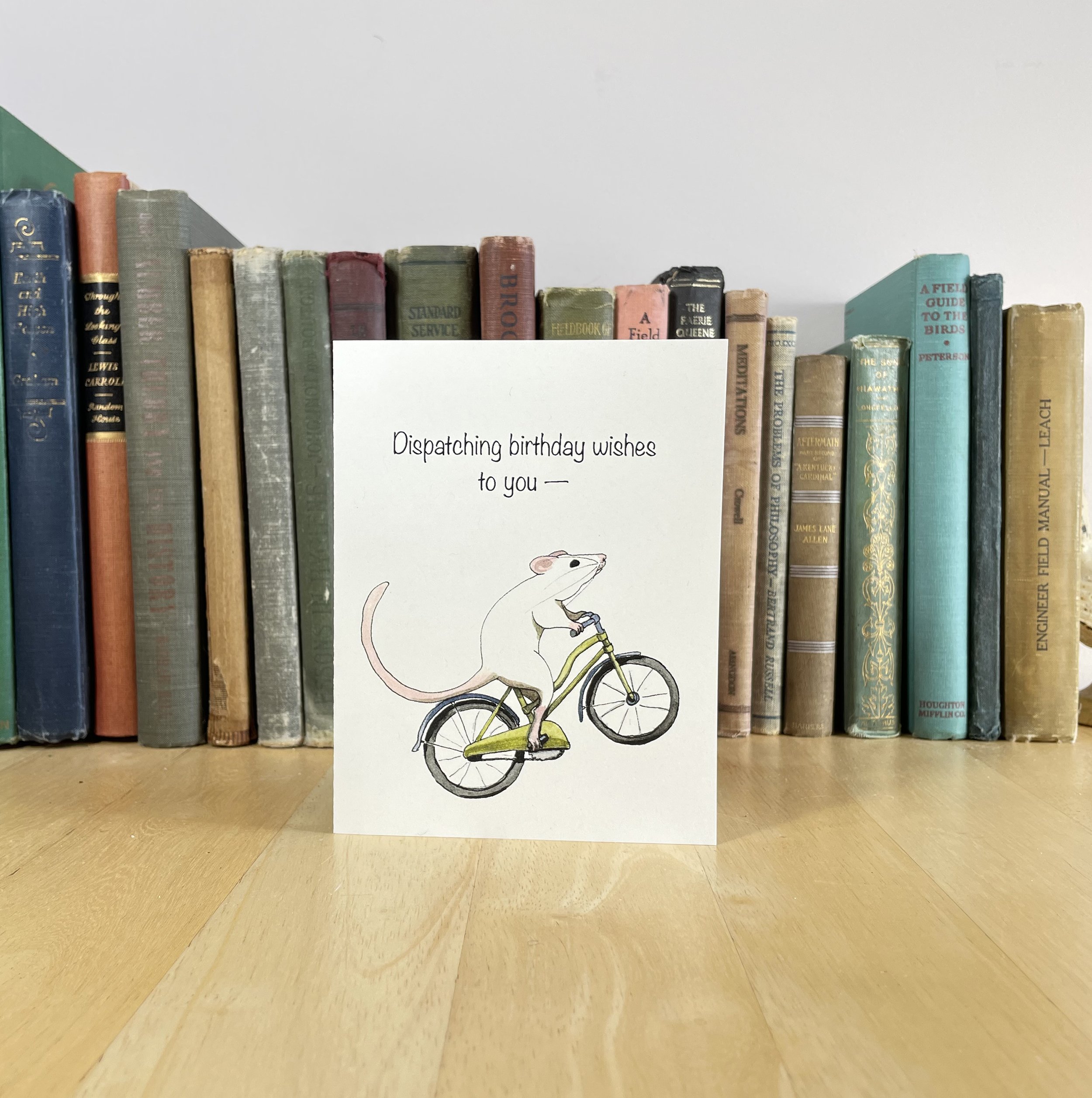Birthday card featuring a white rat on a bicycle