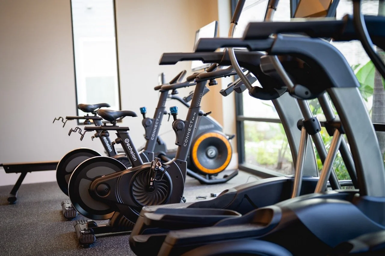 Several exercise bikes and elliptical machines in a fitness room.