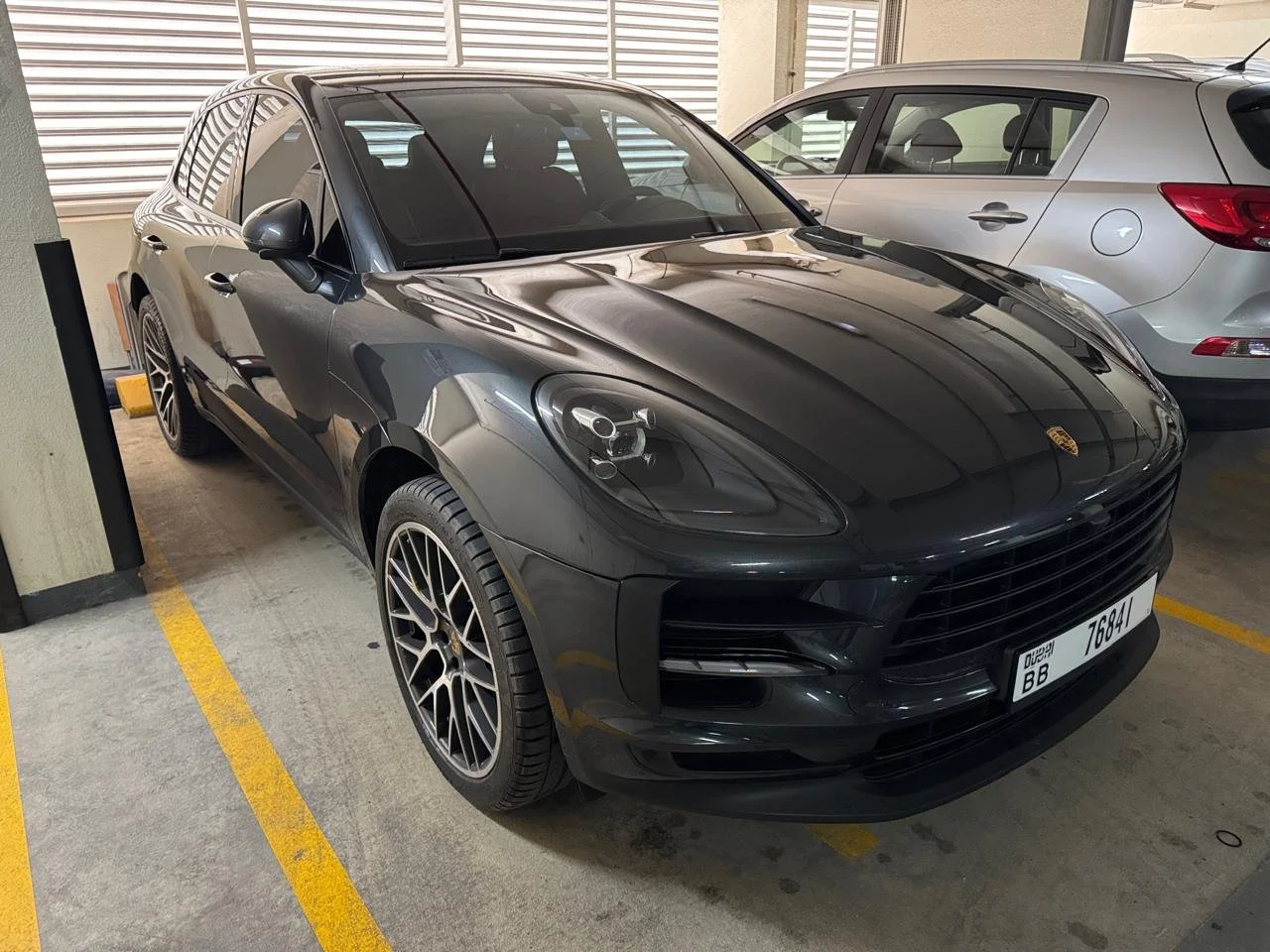Black Porsche sports car parked in Star Centre car body shop next to a silver SUV.
