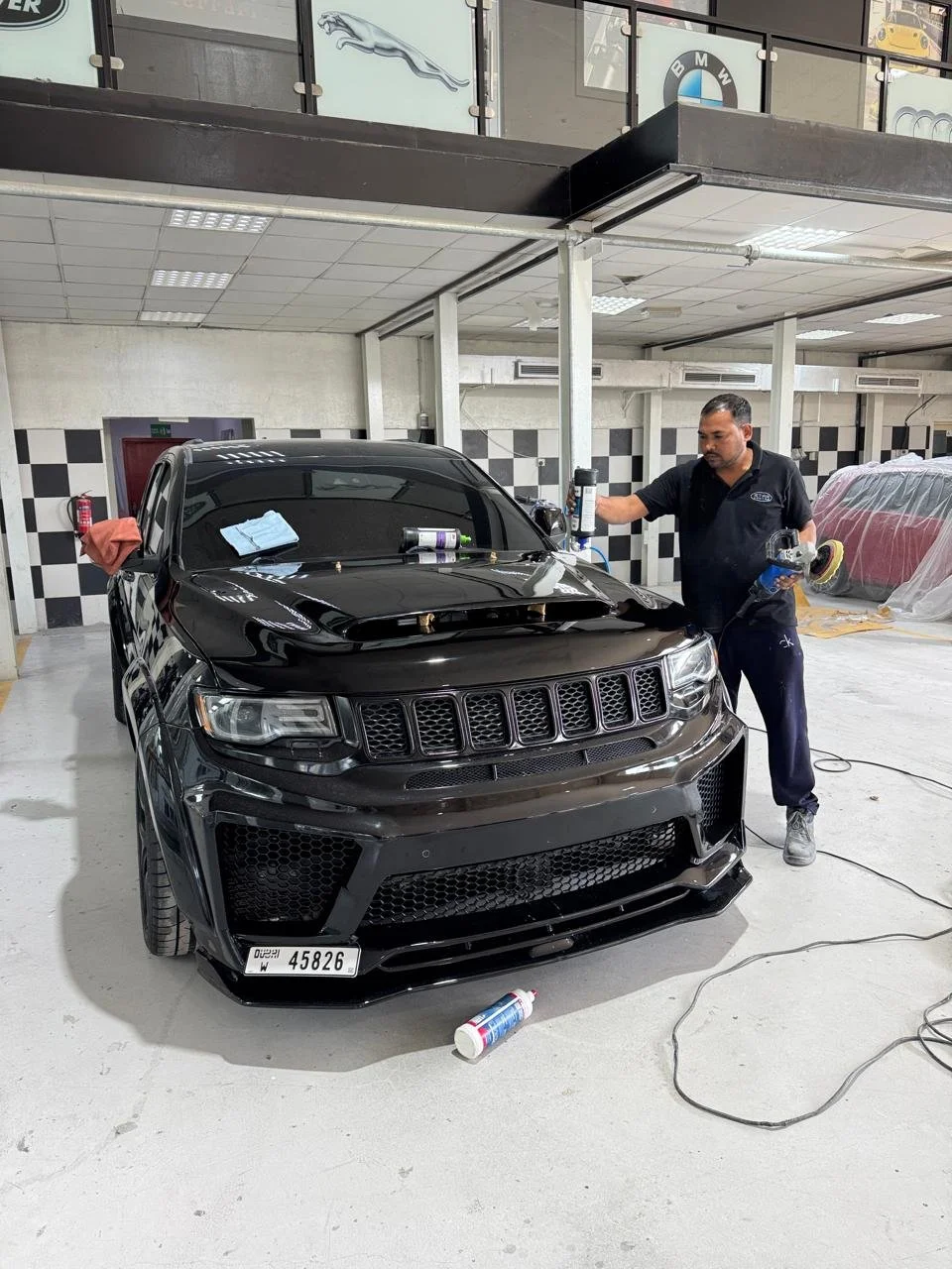 A Star Centre mechanic working on a black car in the Star Centre auto body shop, with tools and supplies around him.