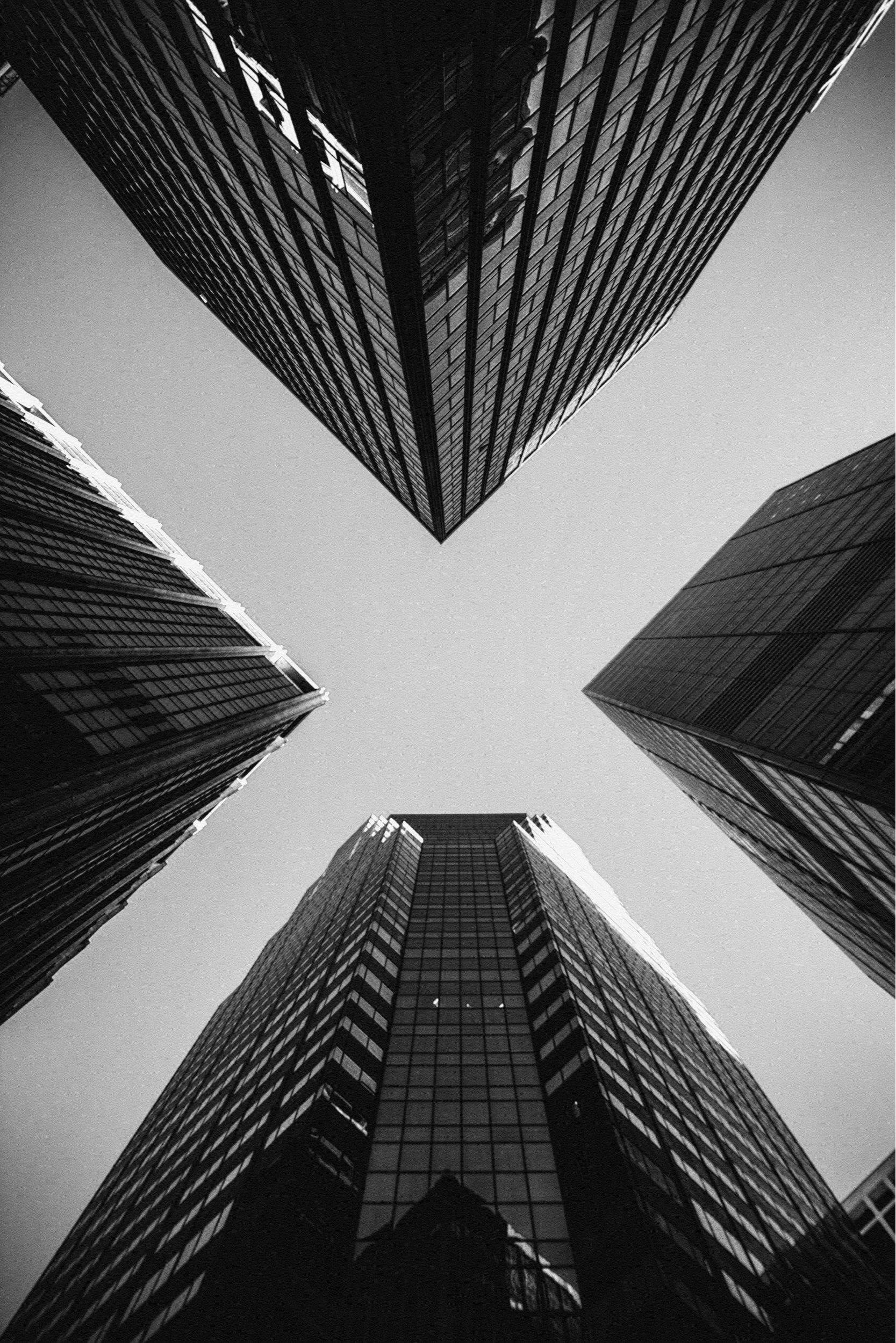 Black and white photo of tall modern glass skyscrapers viewed from ground looking up.