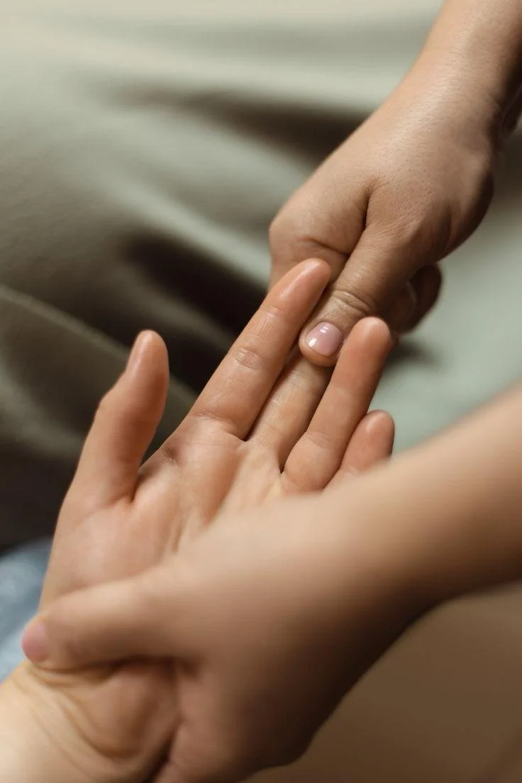Two hands, one appearing older and the other younger, gently touching fingers.