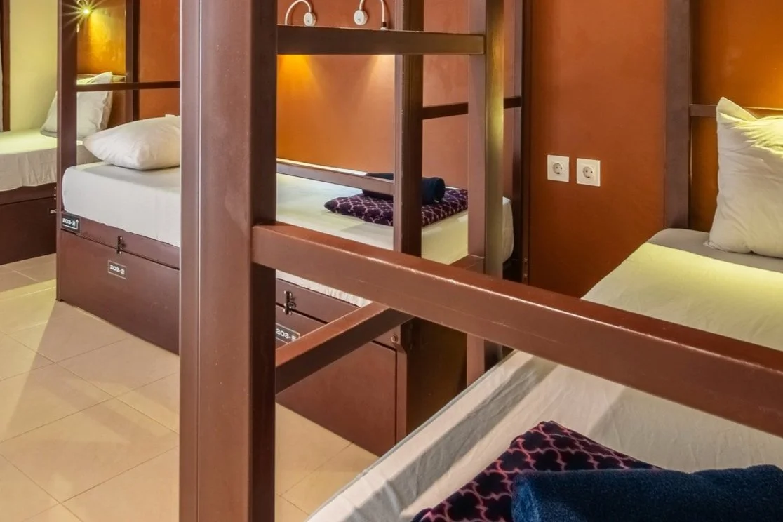 Cozy room with two wooden bunk beds, white bedding, pillows, and wall-mounted reading lights.