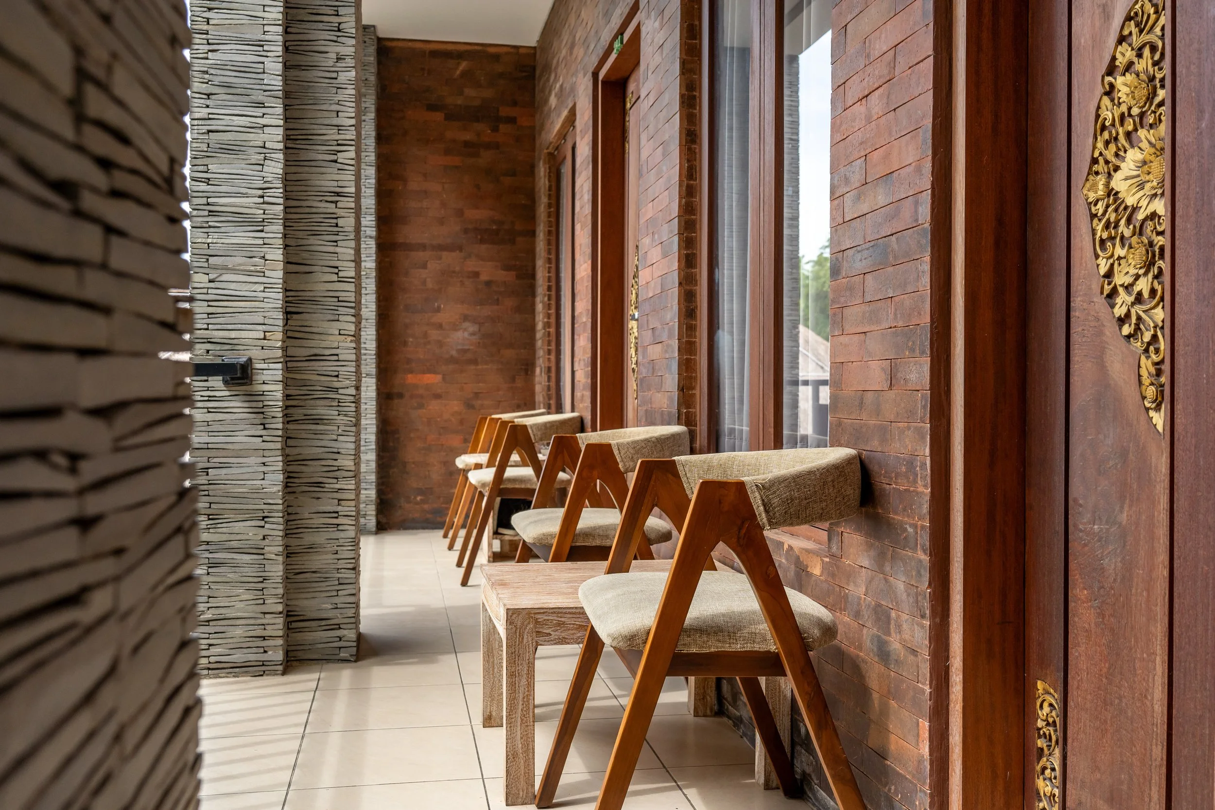 Modern interior with wooden chairs and brick walls on a tiled floor.