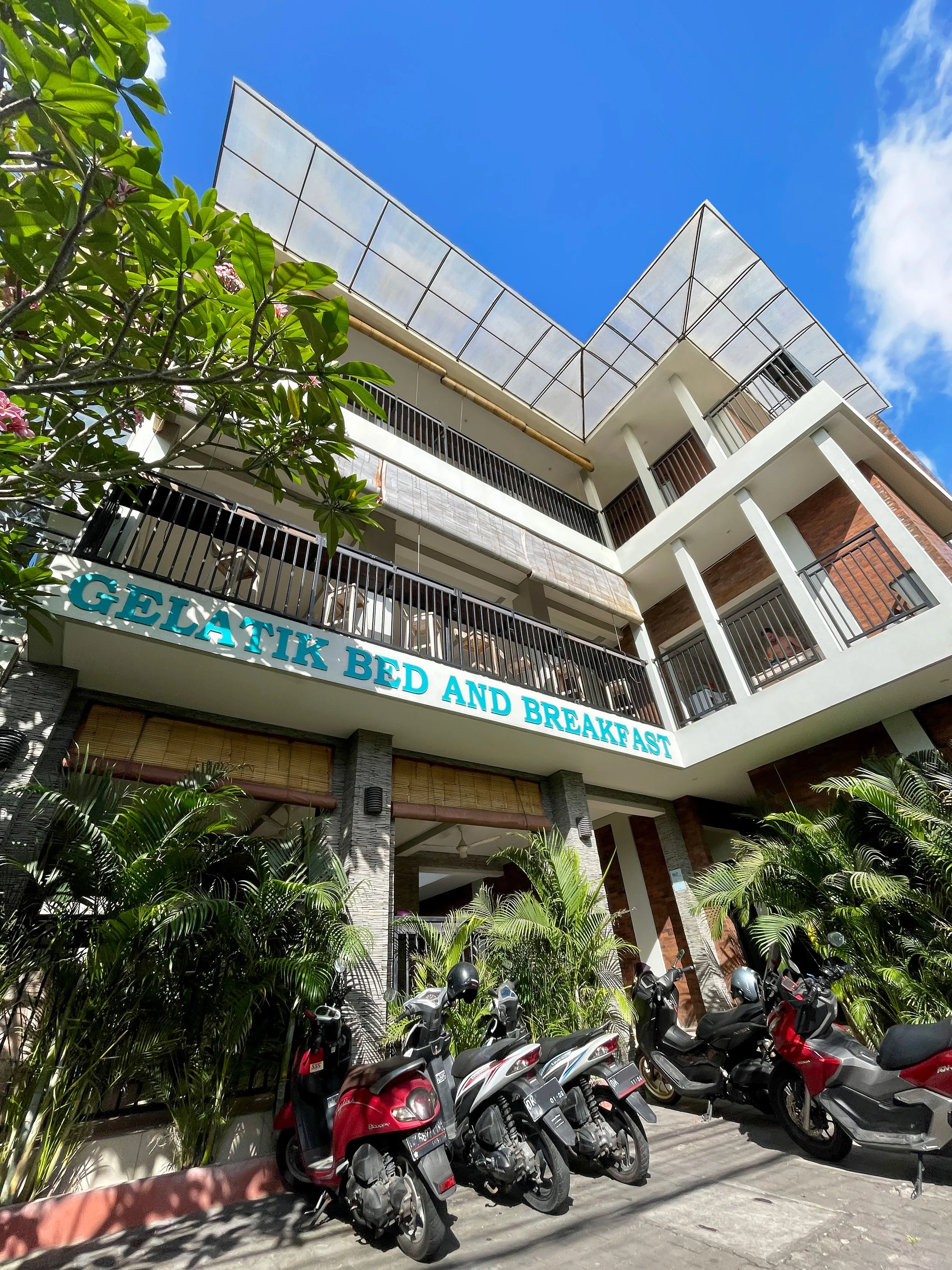 Exterior of Gelatik Bed and Breakfast with scooters parked outside and plants in front
