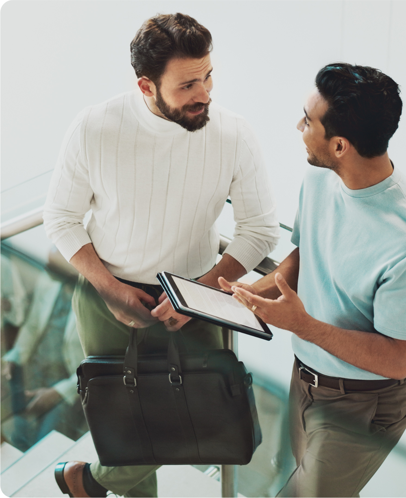 Two men talking while holding a tablet; one has a briefcase