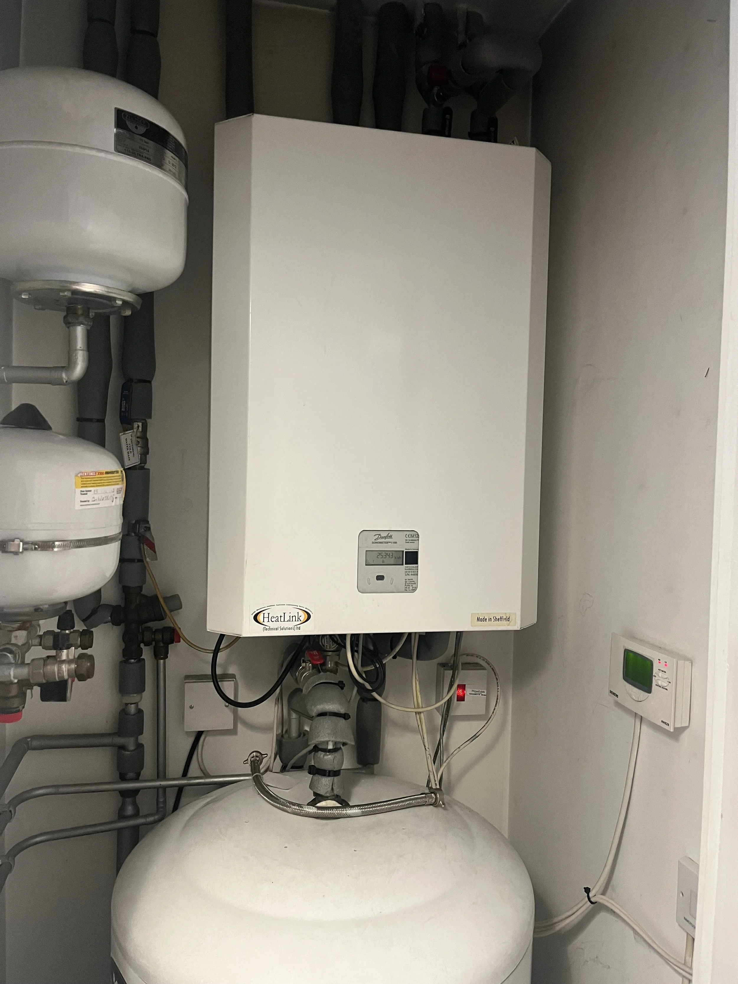 Heatlink heat interface unit installed in a utility cupboard at New Festival Quarter, E14 — cover on, as found on arrival.