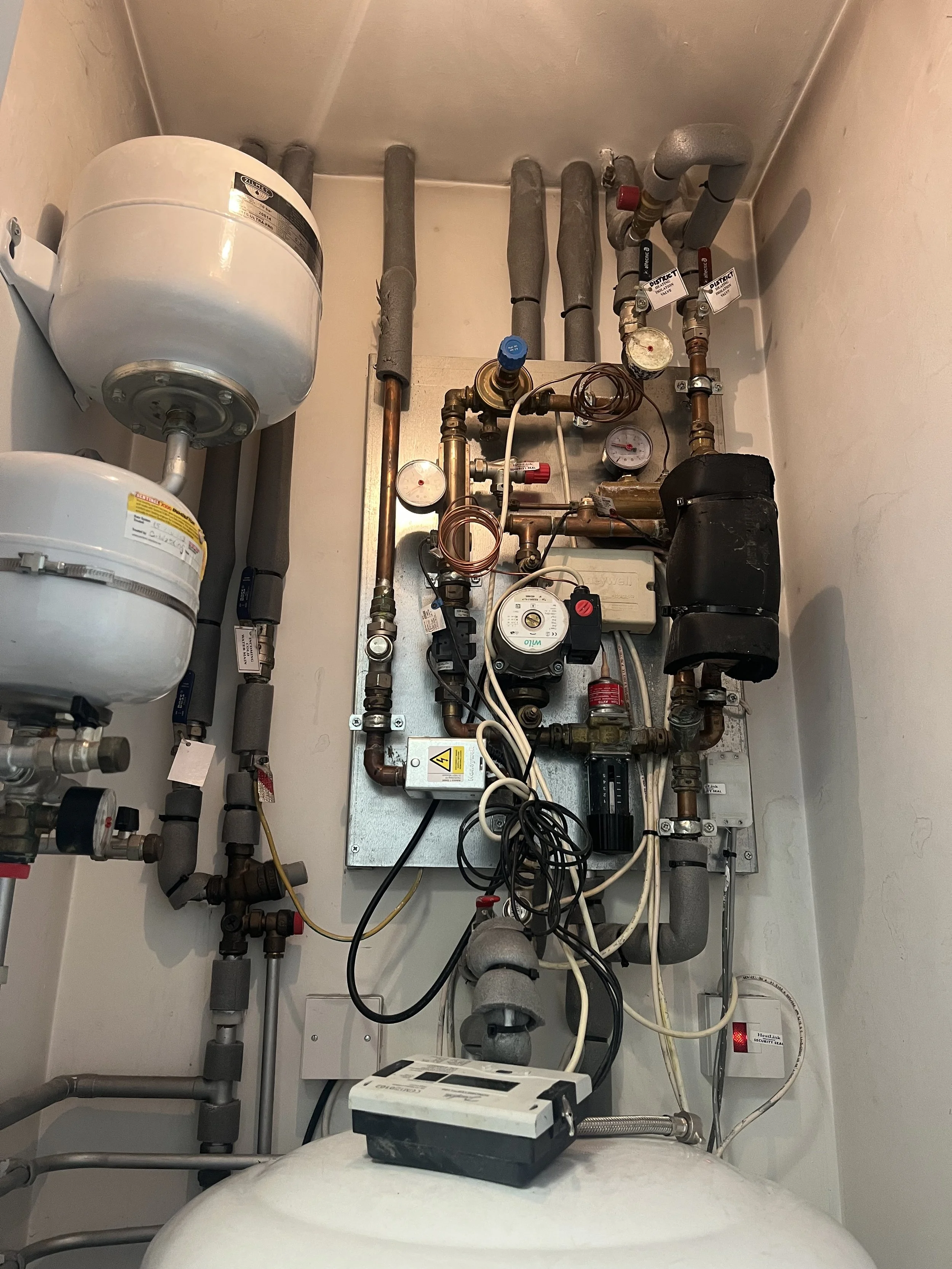 Heatlink HIU opened up for fault finding — internals exposed showing valves, pipework, heat meter, and connections during inspection.