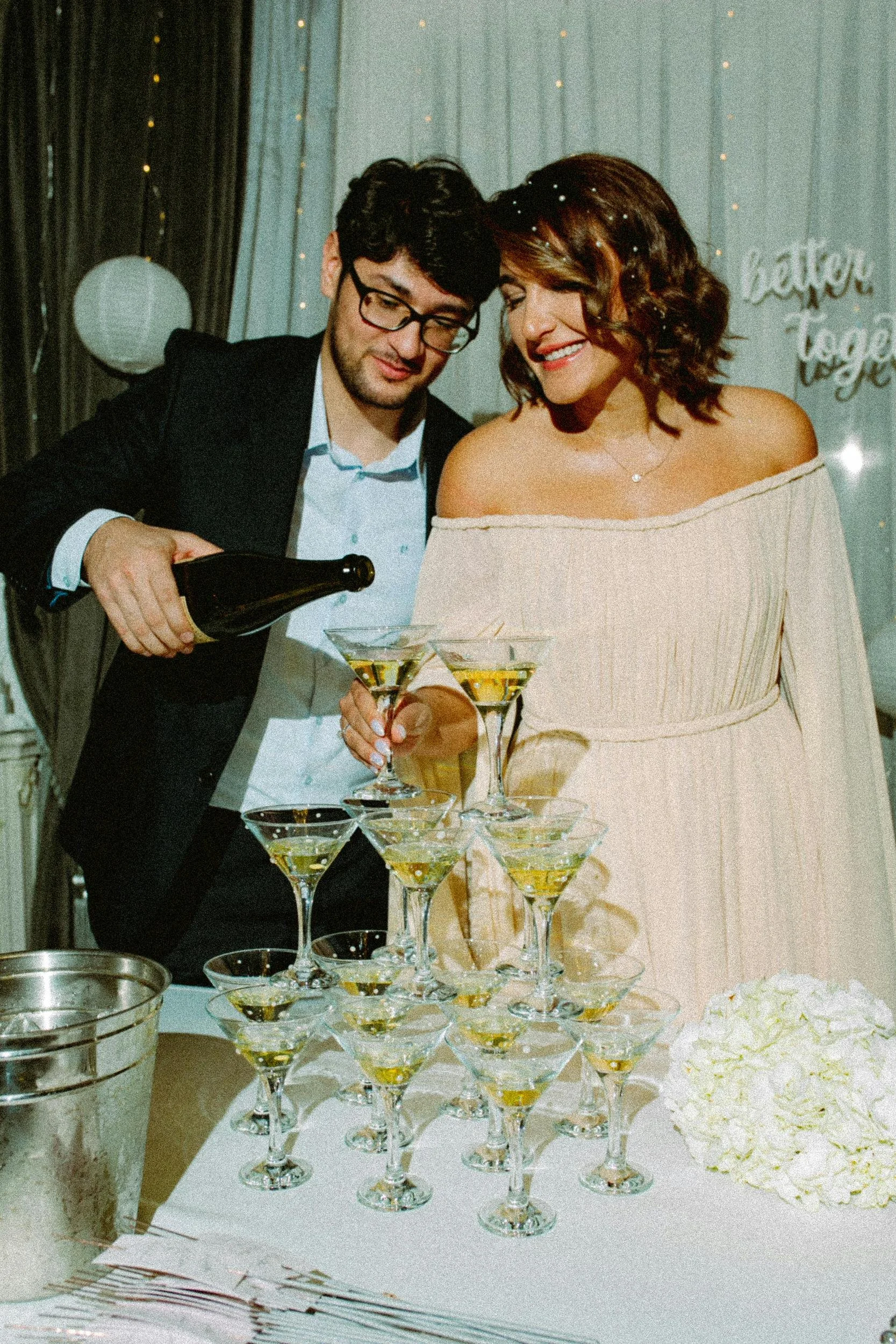 Un homme et une femme habillés élégamment, avec l'homme versant du champagne dans une pyramide de verres.