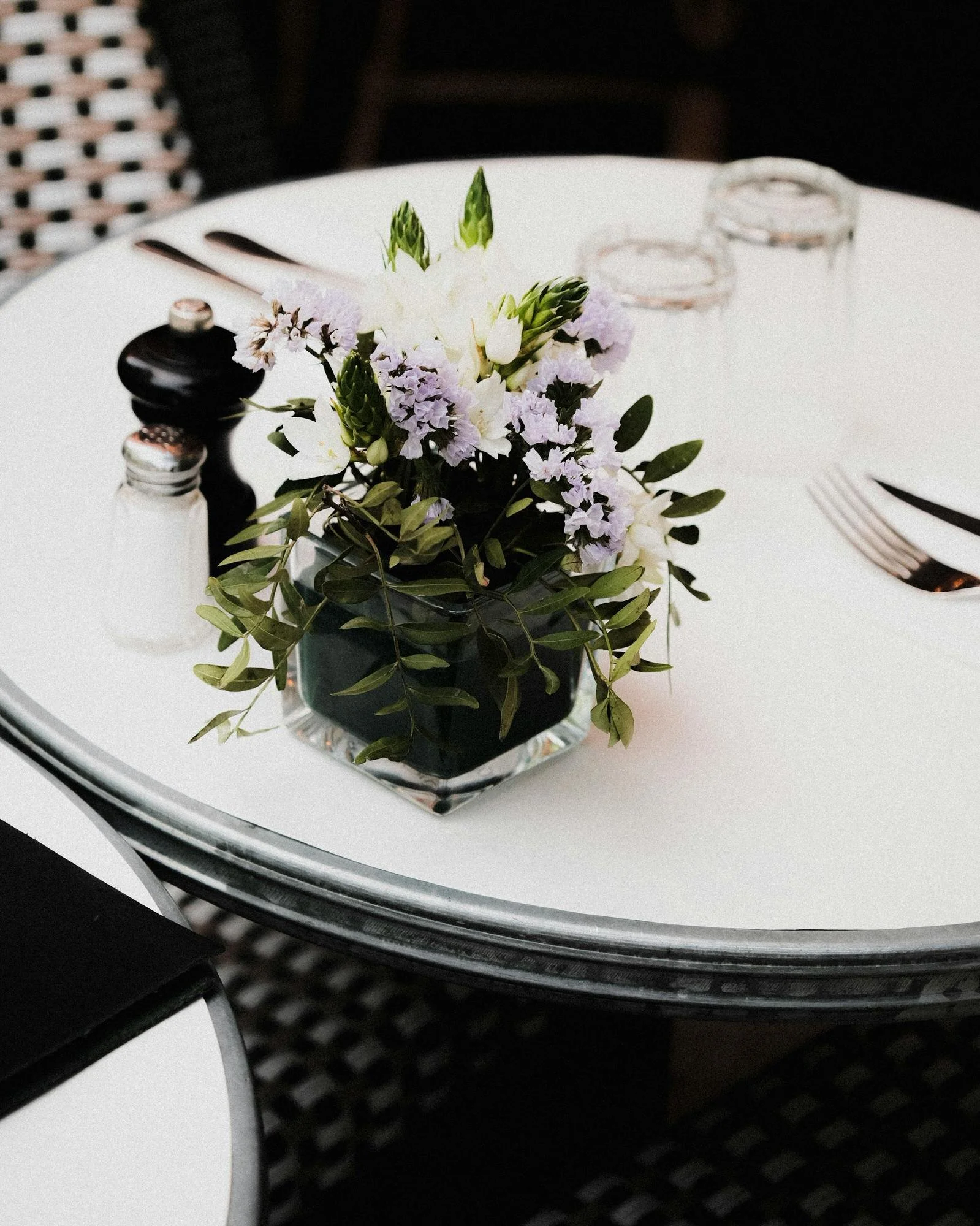 Table de café avec fleurs, sel, poivre et couverts.