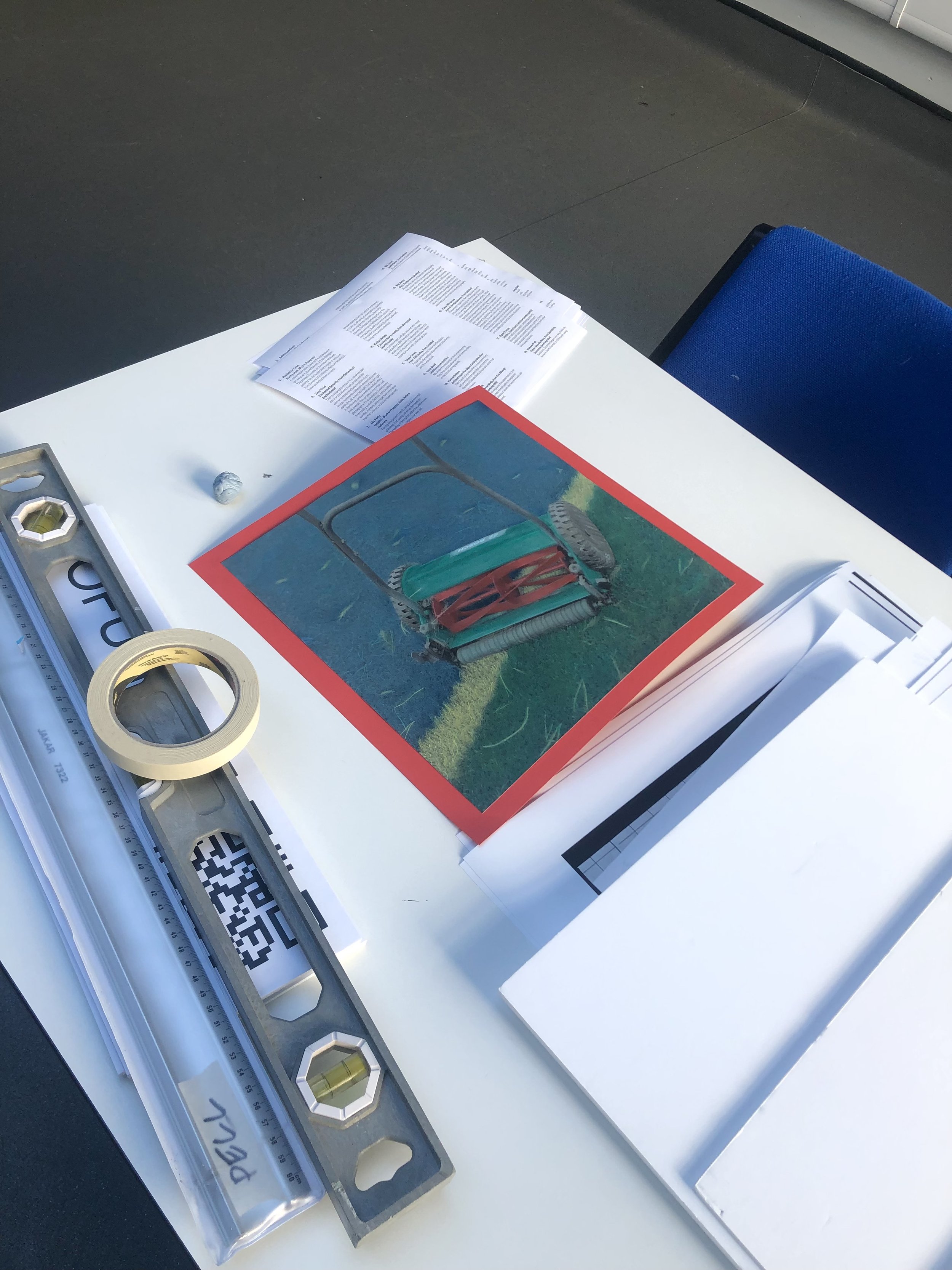 Hand coloured film photograph of lawnmower on a desk.