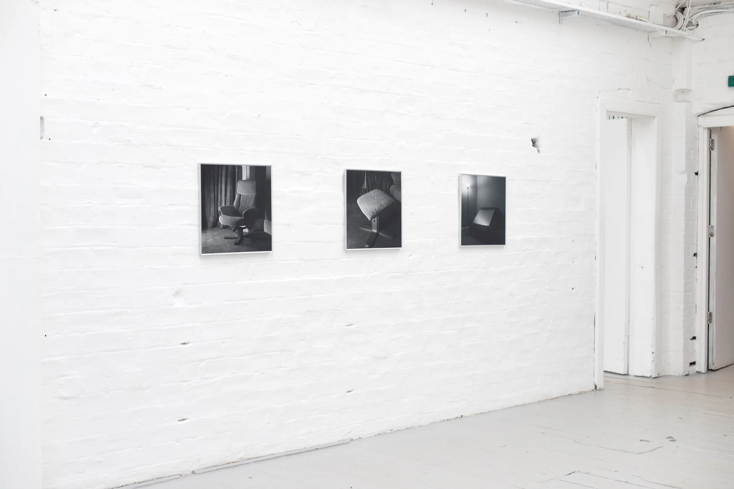 Image of three framed photographs on the wall, black and white photographs of furniture made to look like hostile architecture.