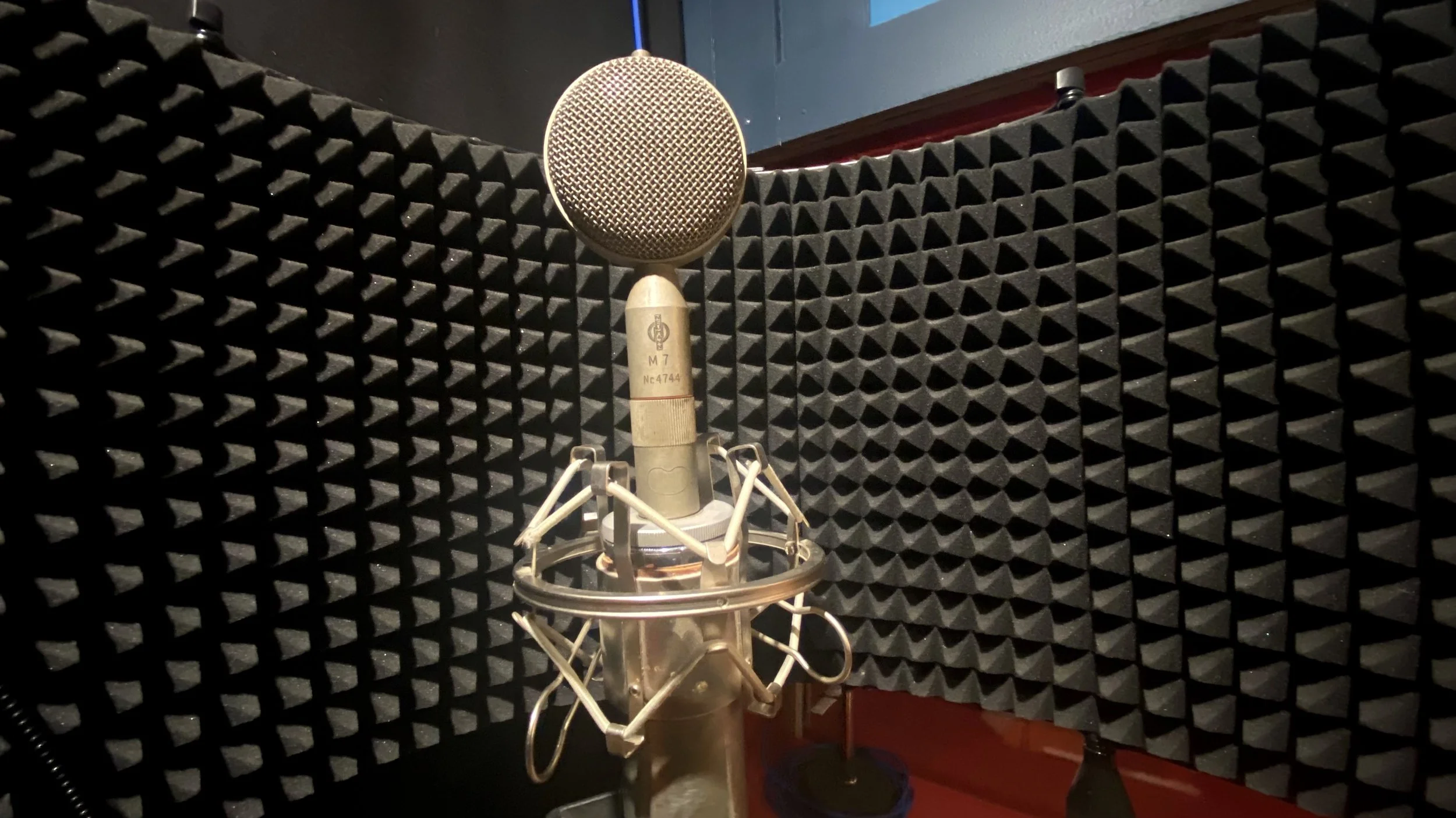 Microphone vintage en studio d'enregistrement avec des panneaux acoustiques noirs en arrière-plan.