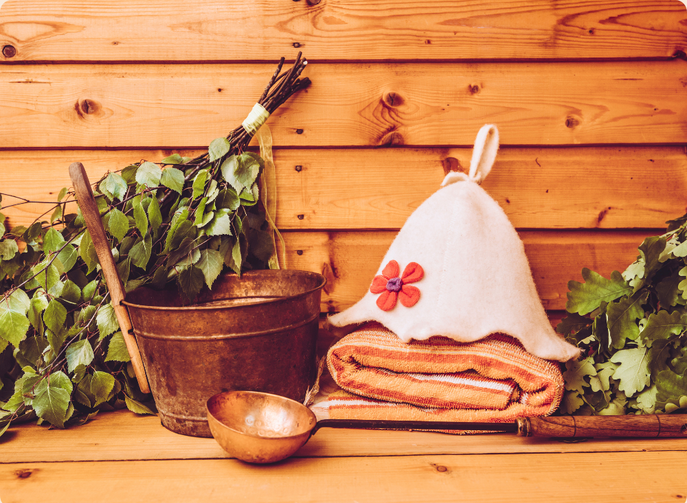 A rustic wooden shelf with a potted plant, a small bowl, a folded towel, a white felt hat with a bunny ear and flower decoration, and a small wooden stick.