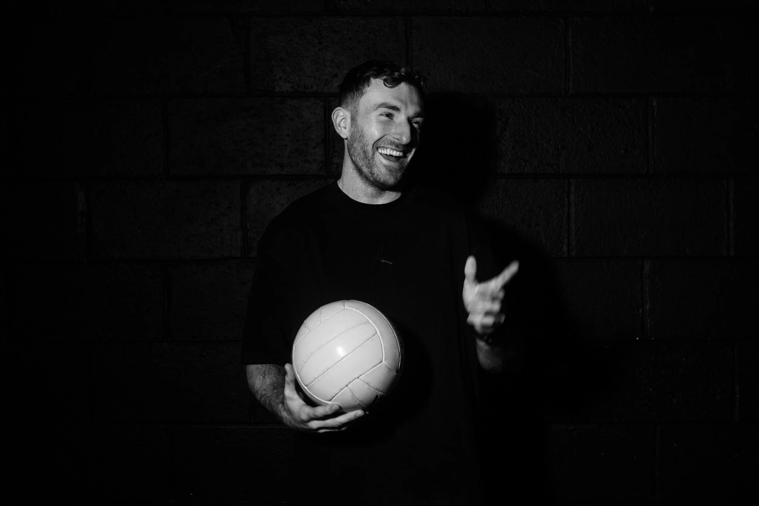 A male athlete in a sports uniform kicking a ball during a game.