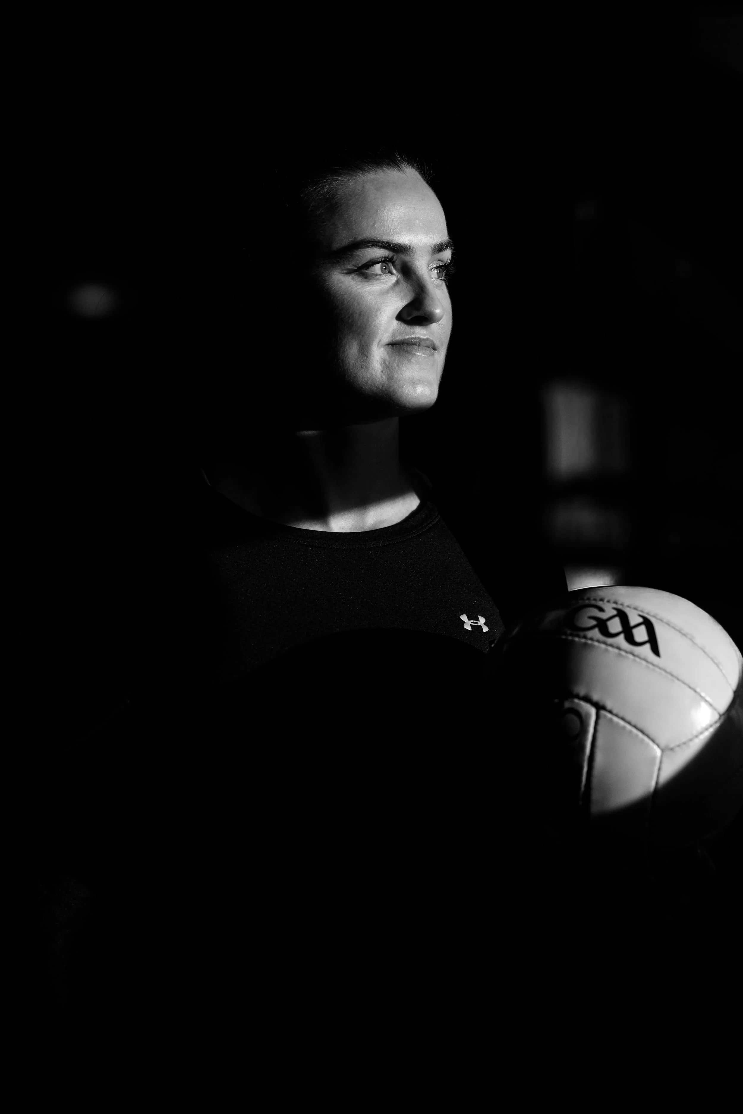 Female player in motion kicking a ball during a game, black and white photo.