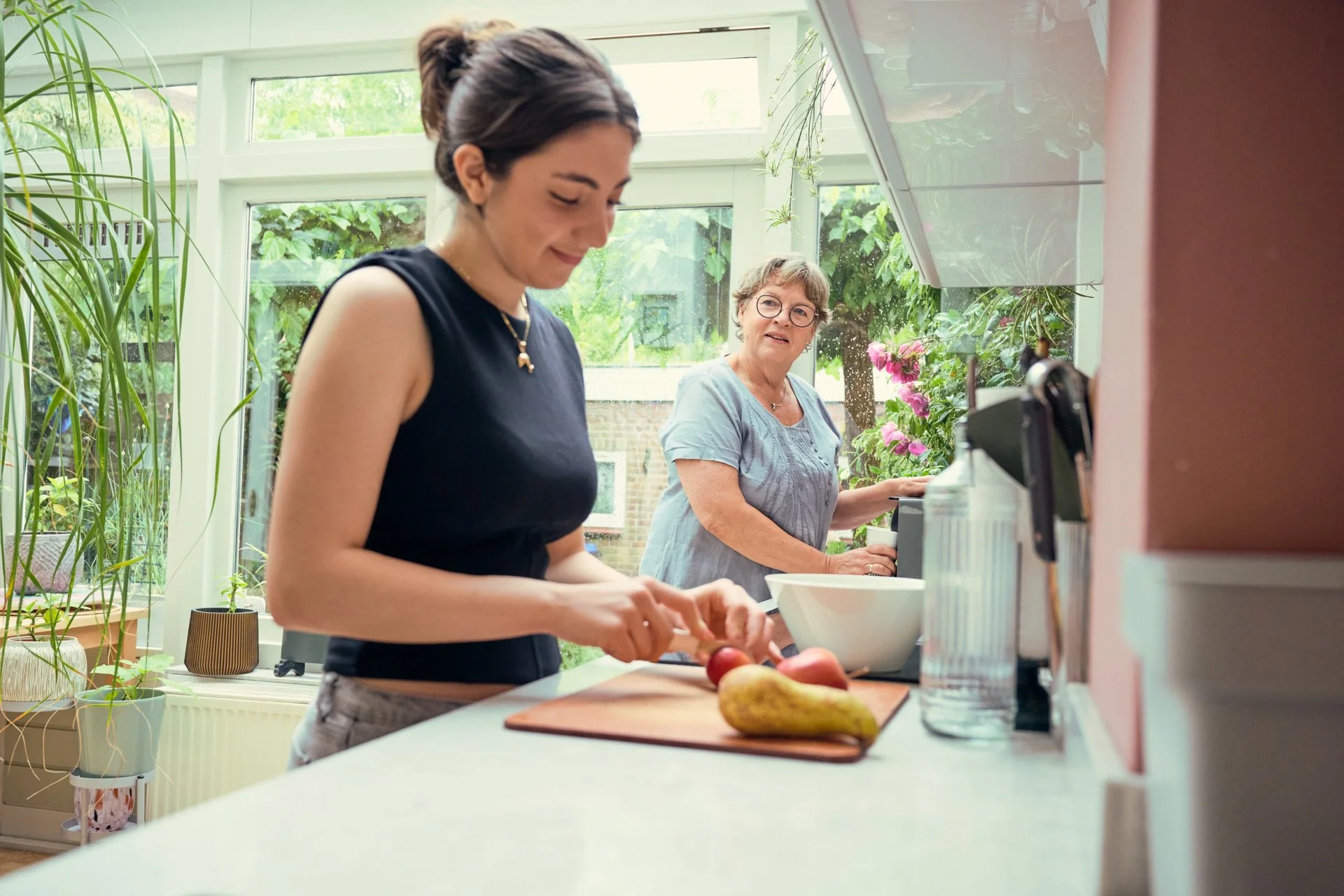 Jonge vrouw en moeder staan te koken in een keuken. 