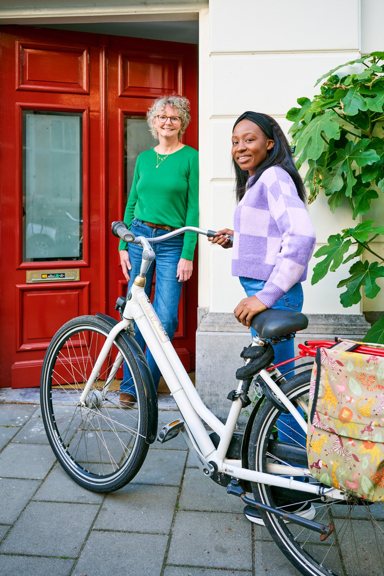 Een jonge zwarte vrouw komt thuis met haar fiets.